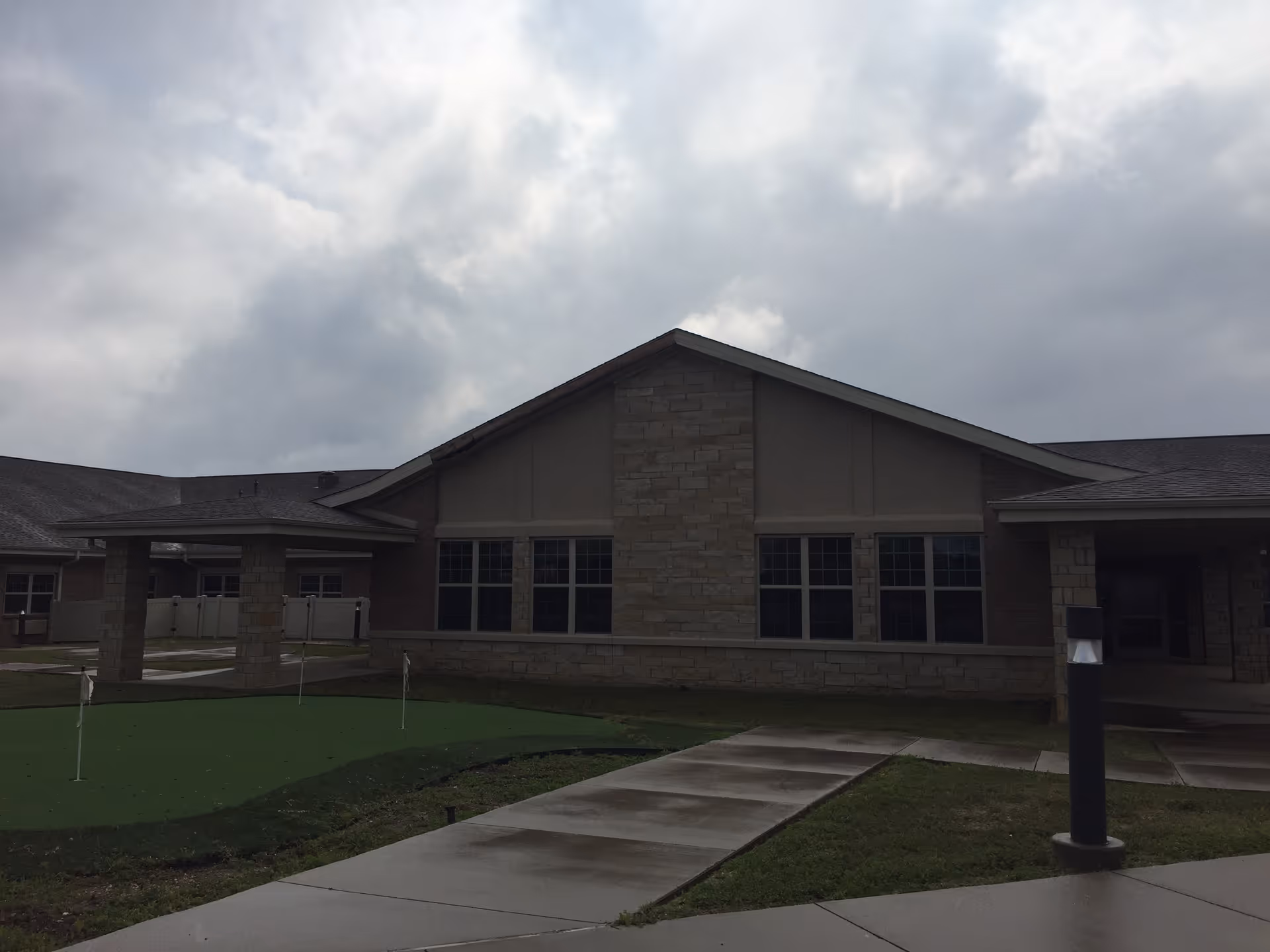 Exterior view of a senior living facility with stone facade and large windows.