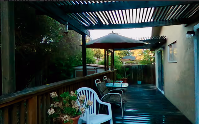 Outdoor deck with seating, a table under an umbrella along the building.