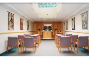 Small interior room with purple upholstered chairs arranged in rows facing a wooden podium.