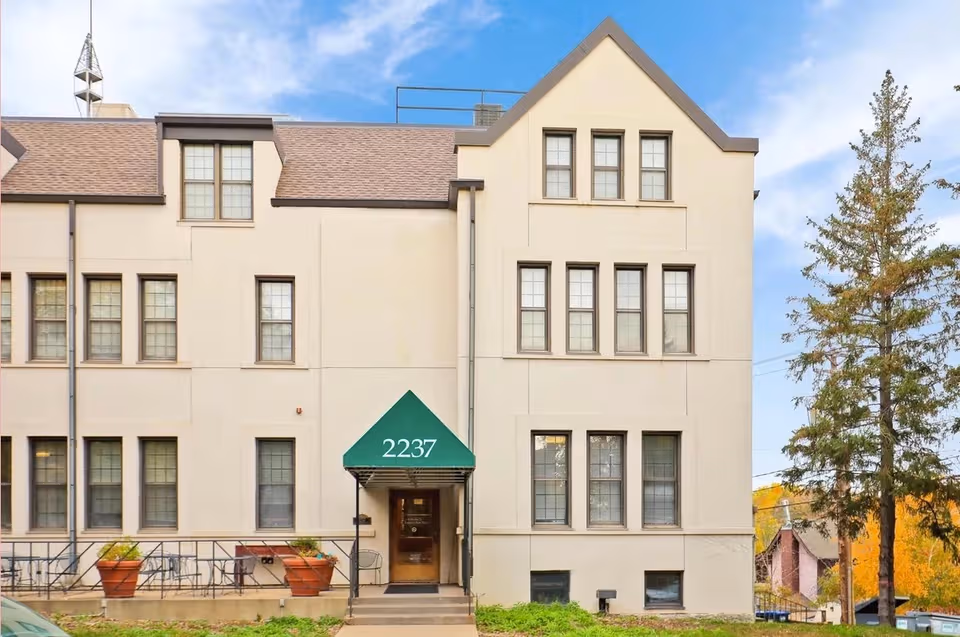 Front facade of St Anthony Park Home, a senior living building with green awning and steps.