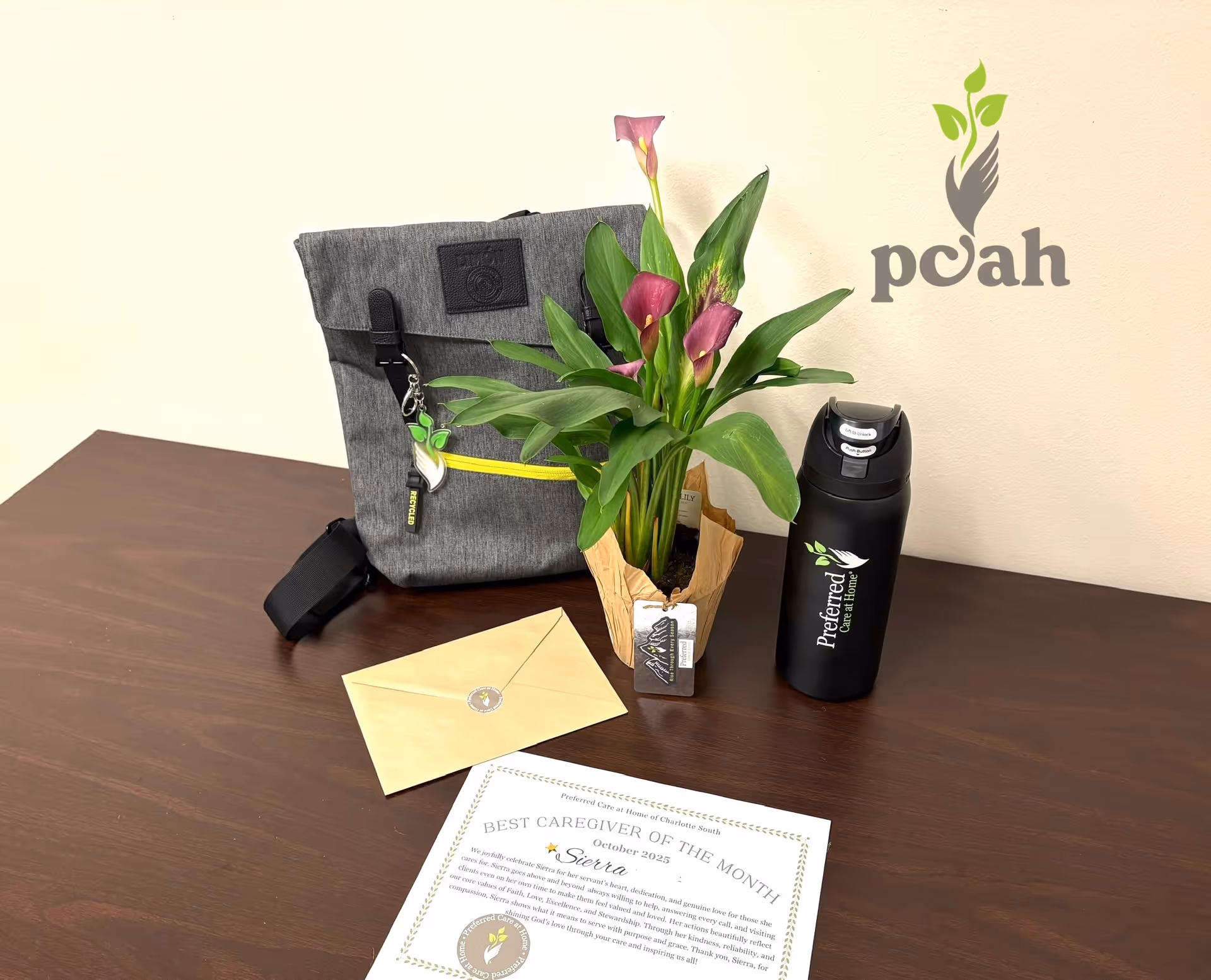 Interior desk setup with flowers, envelope, award certificate, and branded water bottle.
