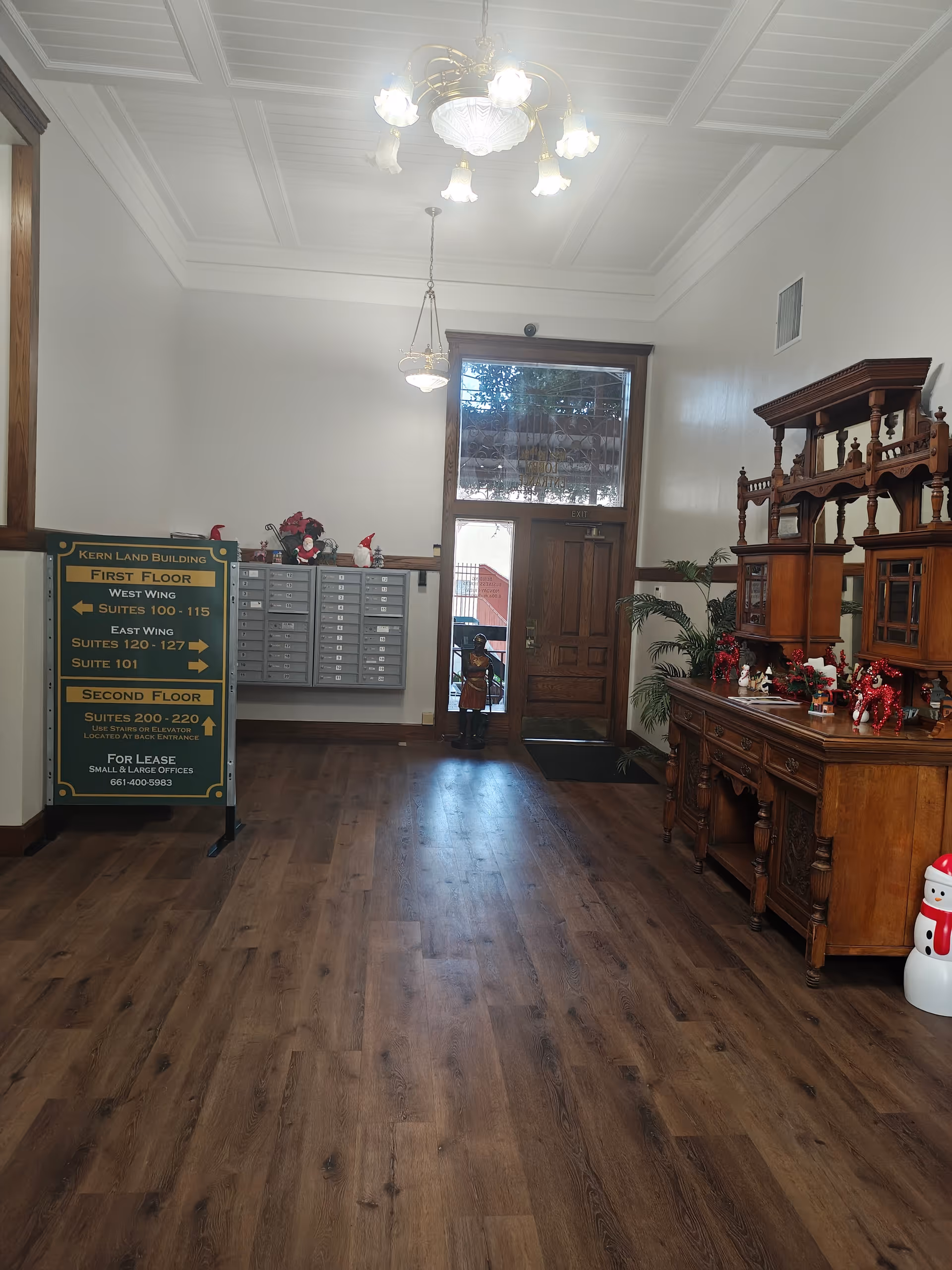An interior lobby of a senior living facility with wooden desk, mailboxes, sign, and holiday decor.