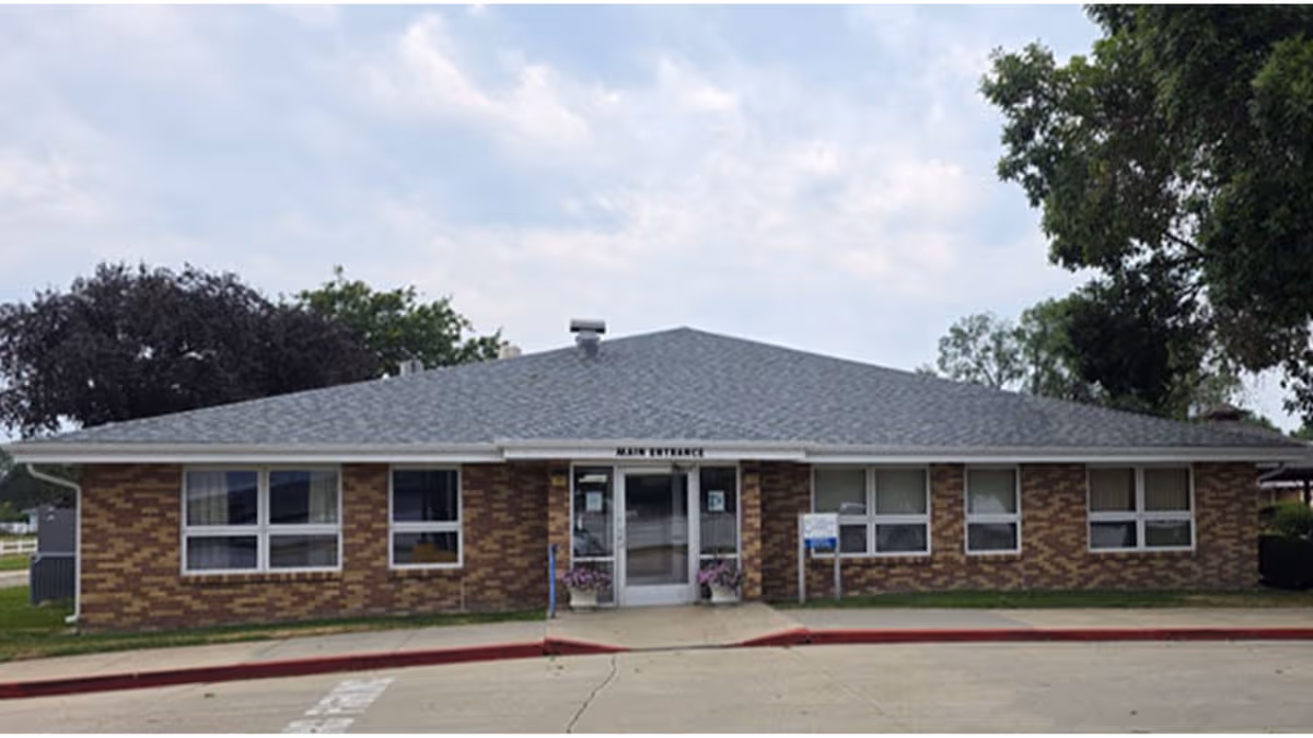 Exterior view of a single-story brick senior living facility with front entrance and windows.