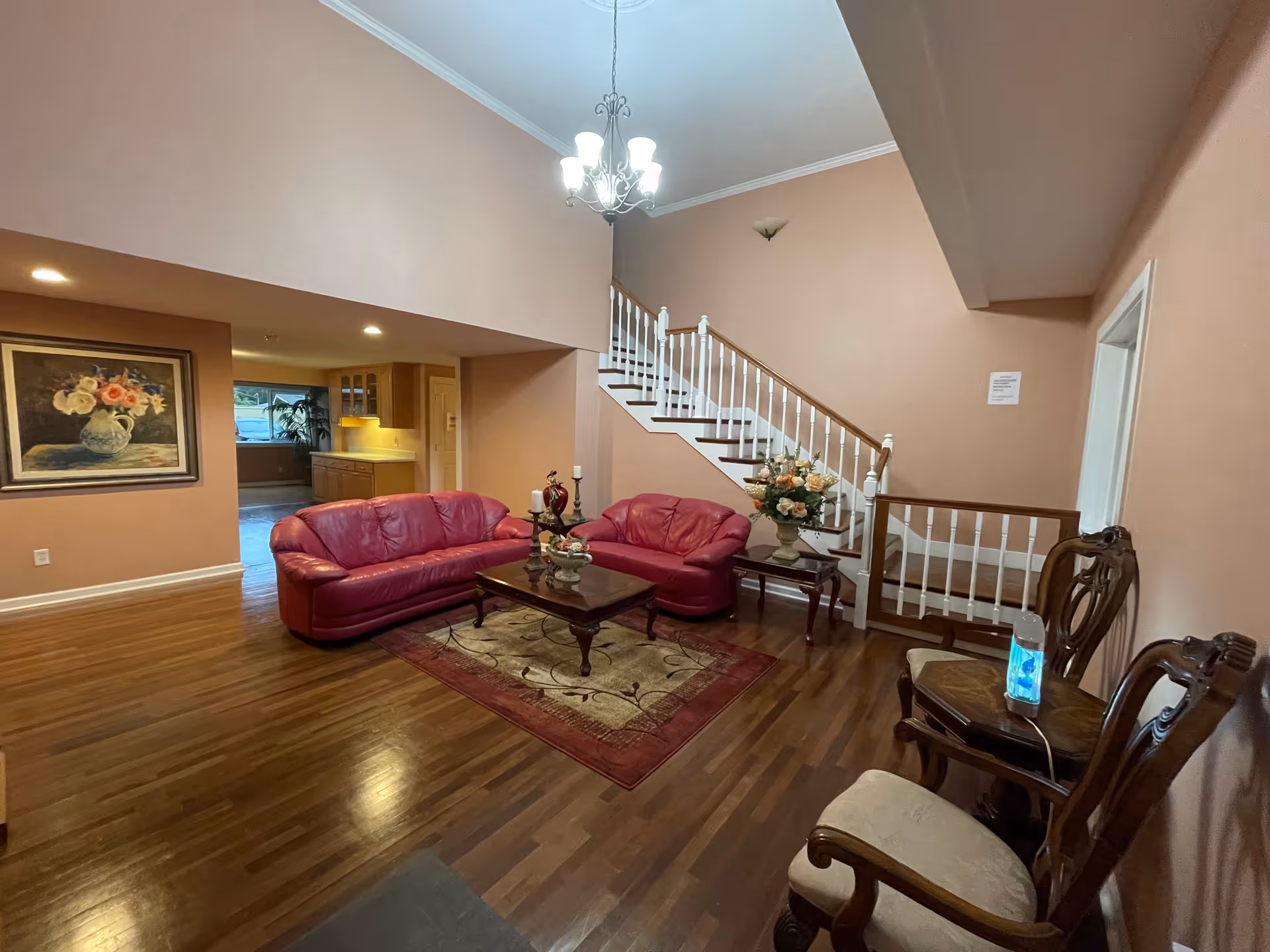 Luxurious living room in a senior facility with red leather sofas and a staircase.