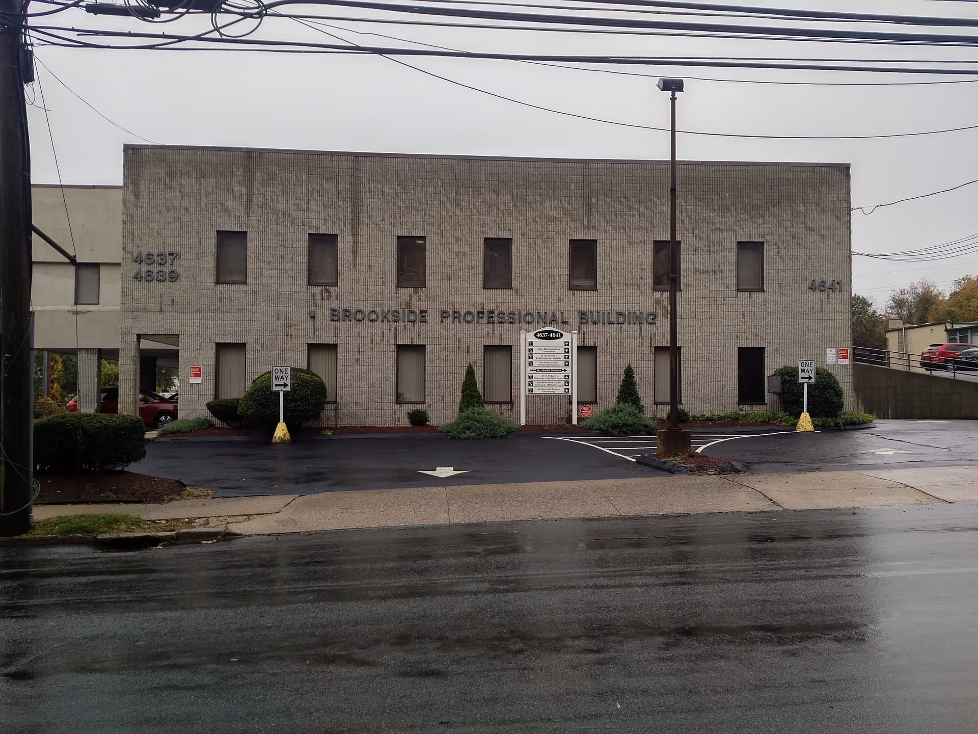 Front exterior of Brookside Professional Building with parking lot and overcast sky.