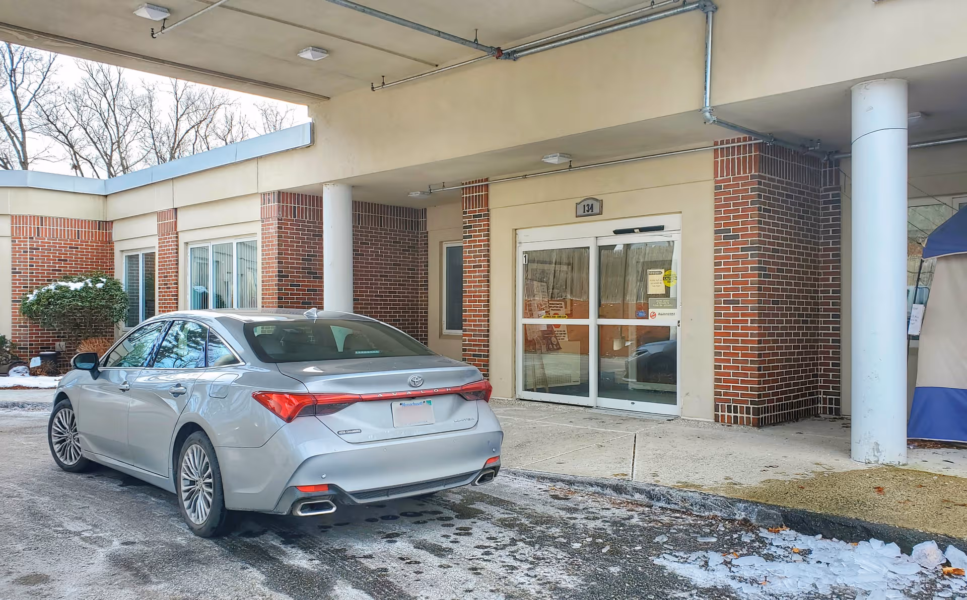 Silver sedan parked near the brick entrance of a senior living facility.