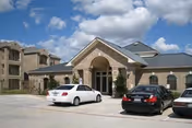 Exterior view of Bay Village of Sarasota facility with parked cars in front.