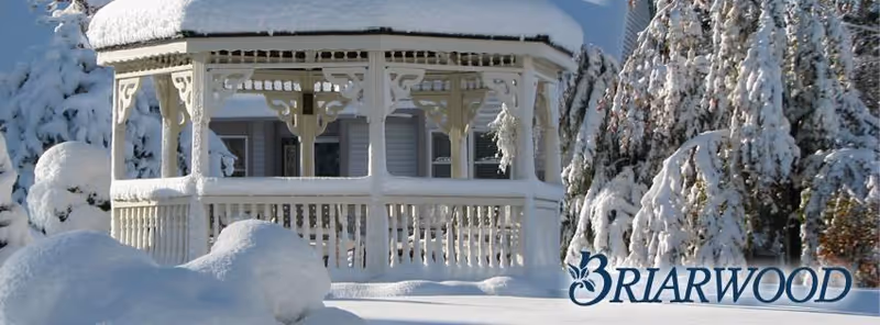 A snow-covered gazebo sits in a wintry landscape beside Briarwood Community.