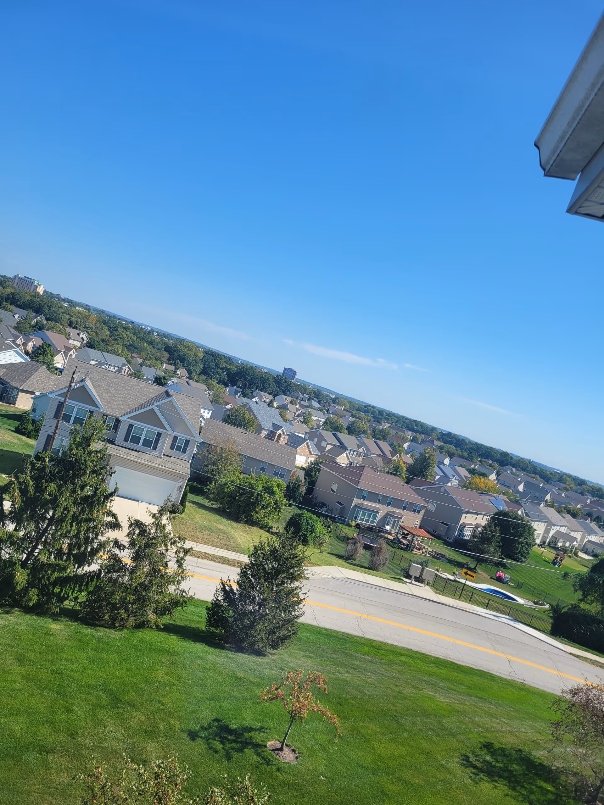 Exterior view of a suburban neighborhood with houses, trees, and a blue sky.