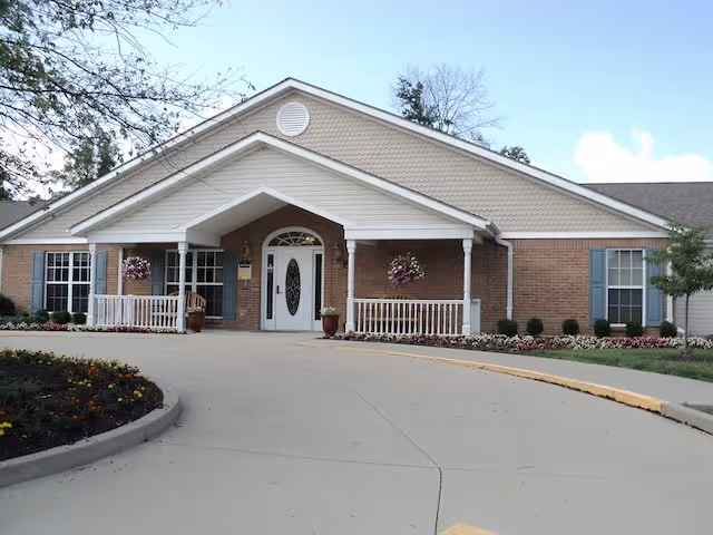 Arden Courts Kenwood senior living entrance with brick exterior and hanging baskets.