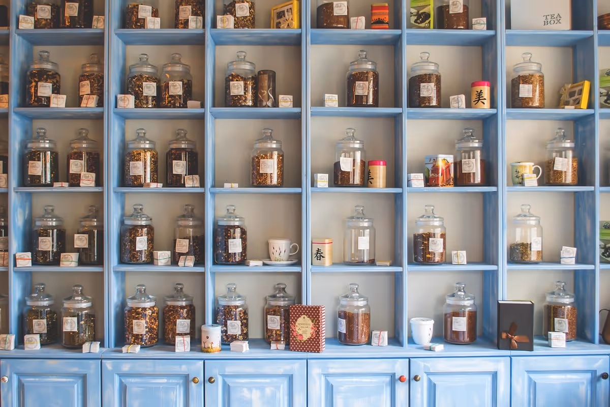 Blue wooden shelves filled with glass jars of herbs and tea boxes.