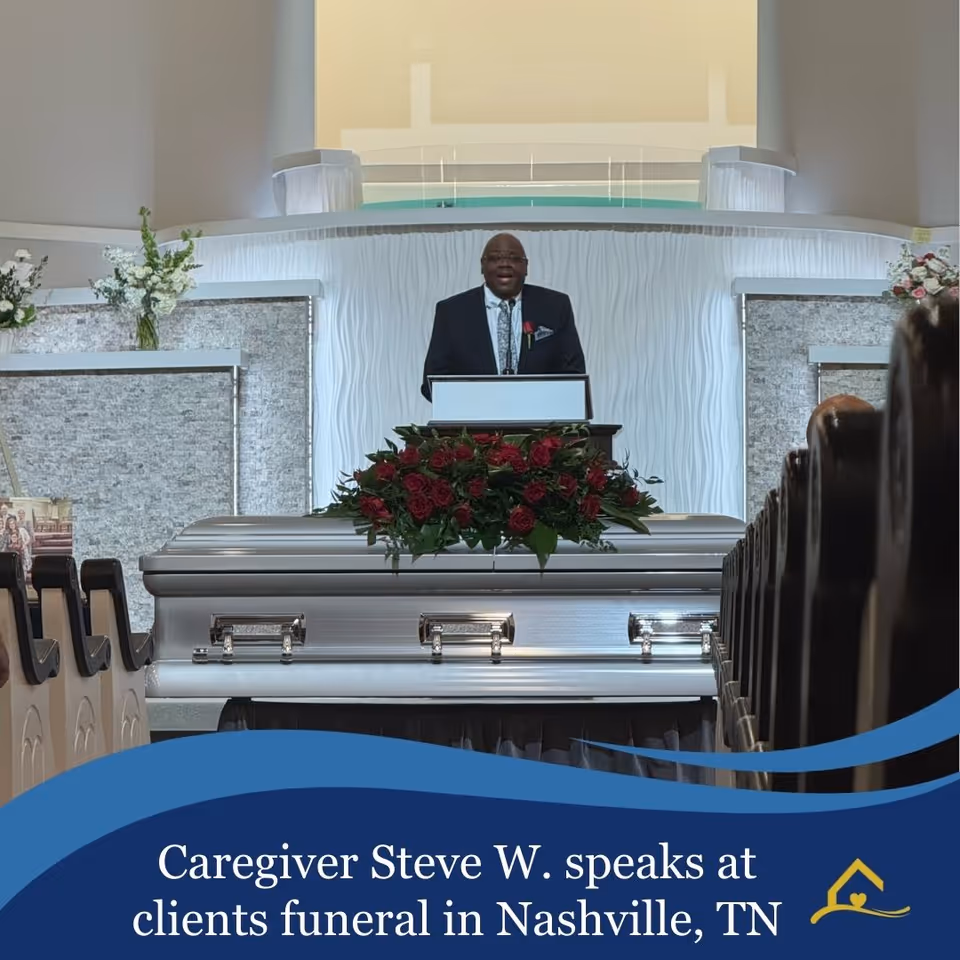 A man in a suit speaks at a podium beside a flower-adorned casket in a church.