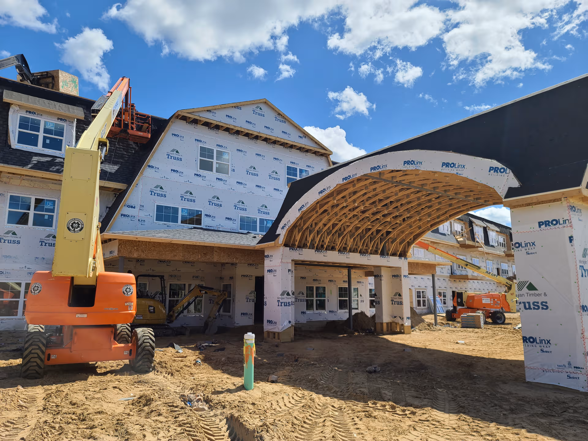 Under-construction Cascade Trails Senior Living exterior with curved entrance arch and heavy machinery.