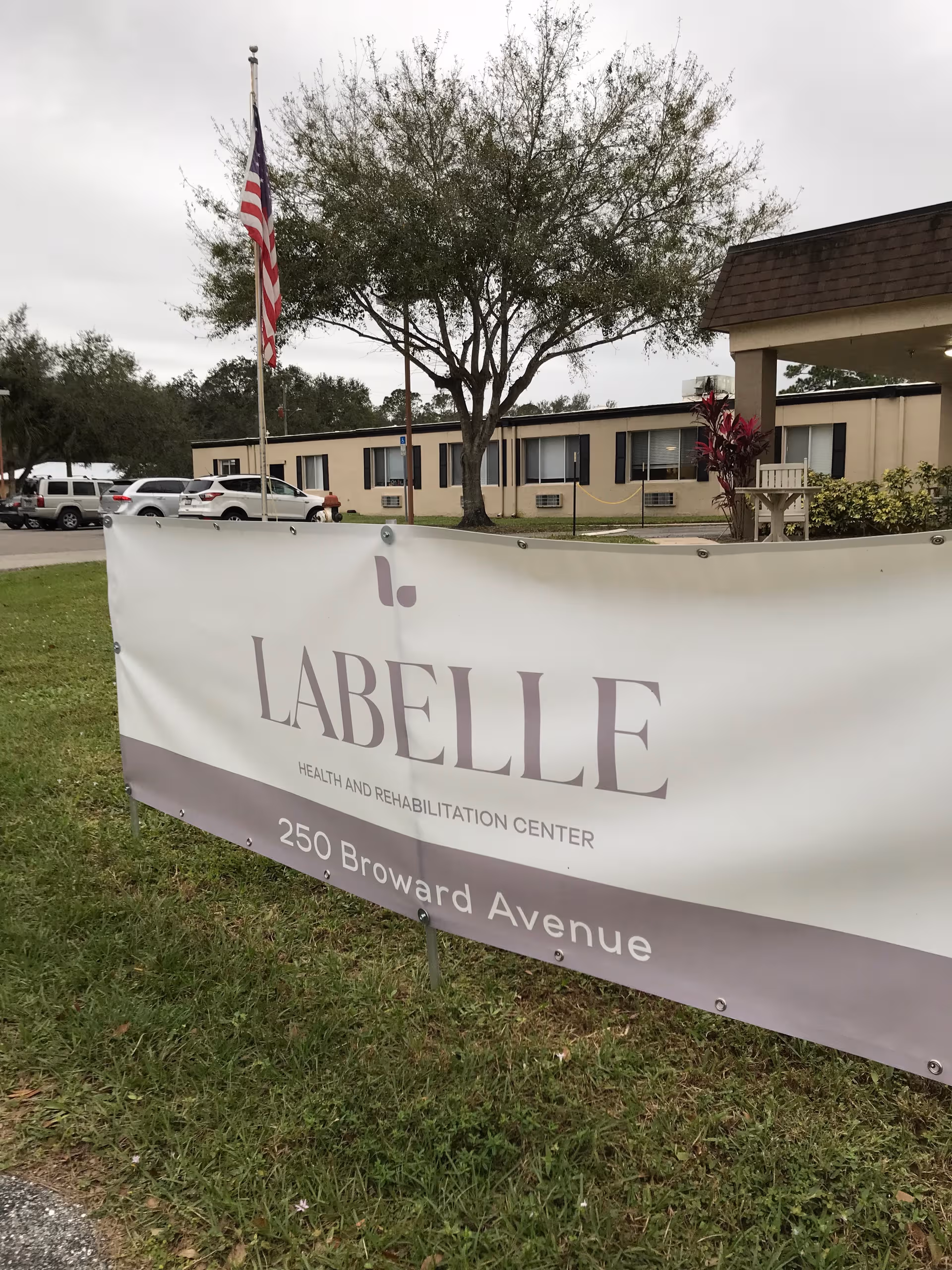 Outdoor view of LaBelle Health and Rehabilitation Center with banner and parked cars.