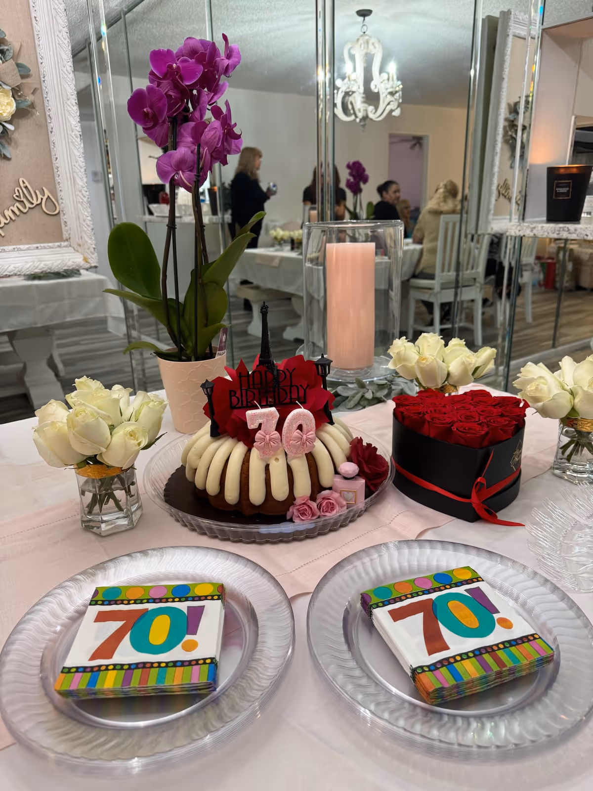 Birthday cake centerpiece with flowers and candles on a dining room table.