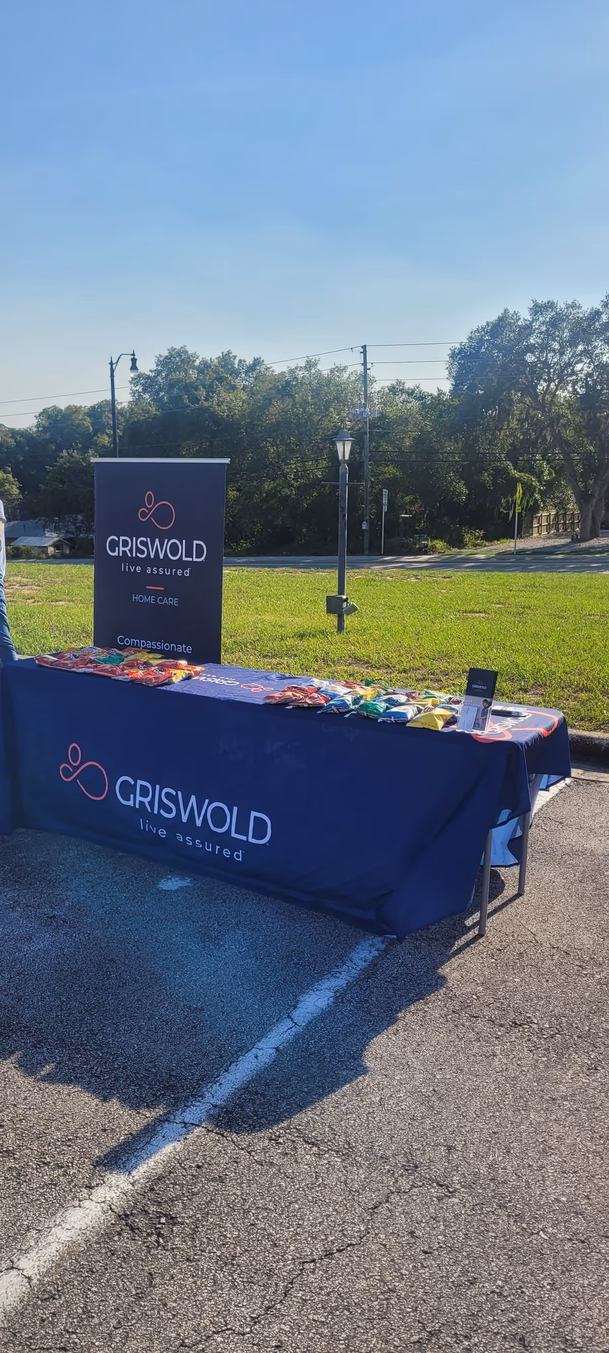 Outdoor table display with Griswold banners and promotional materials in a parking lot.