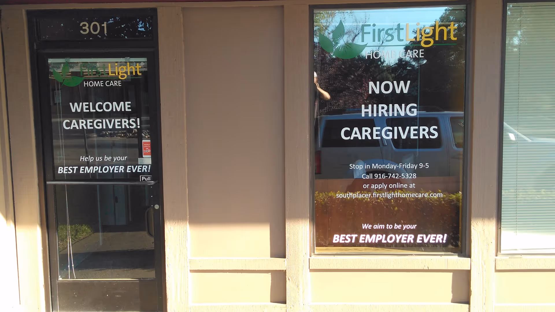 Storefront of FirstLight Home Care with Now Hiring Caregivers signs in the windows.
