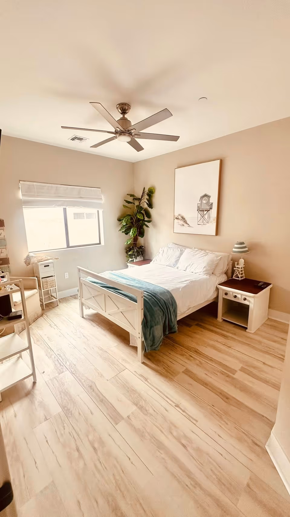 Bright bedroom with white bed, nightstands, plant, window, and ceiling fan.