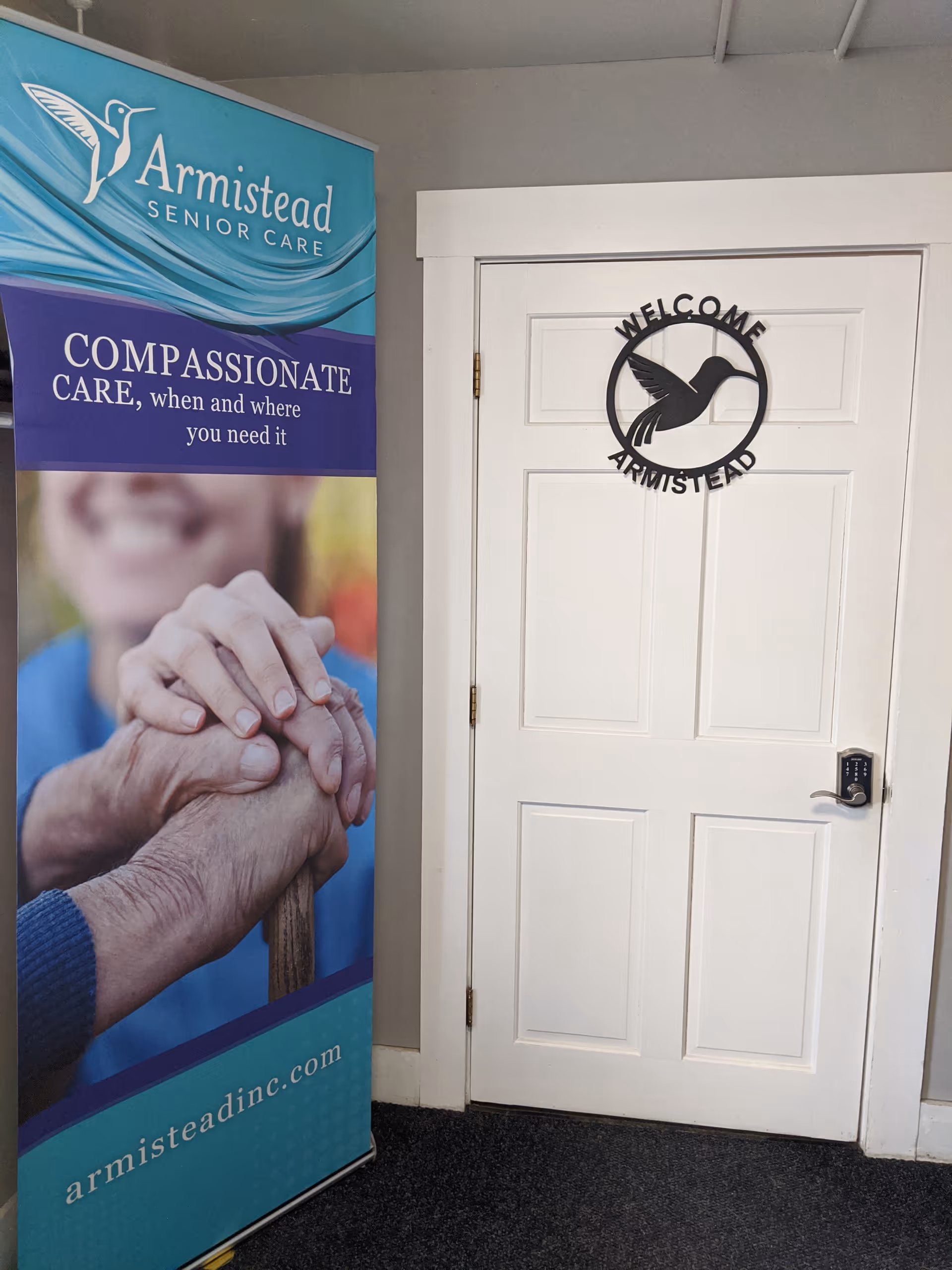 Indoor entrance area with Armistead Senior Care banner beside a white welcome door.