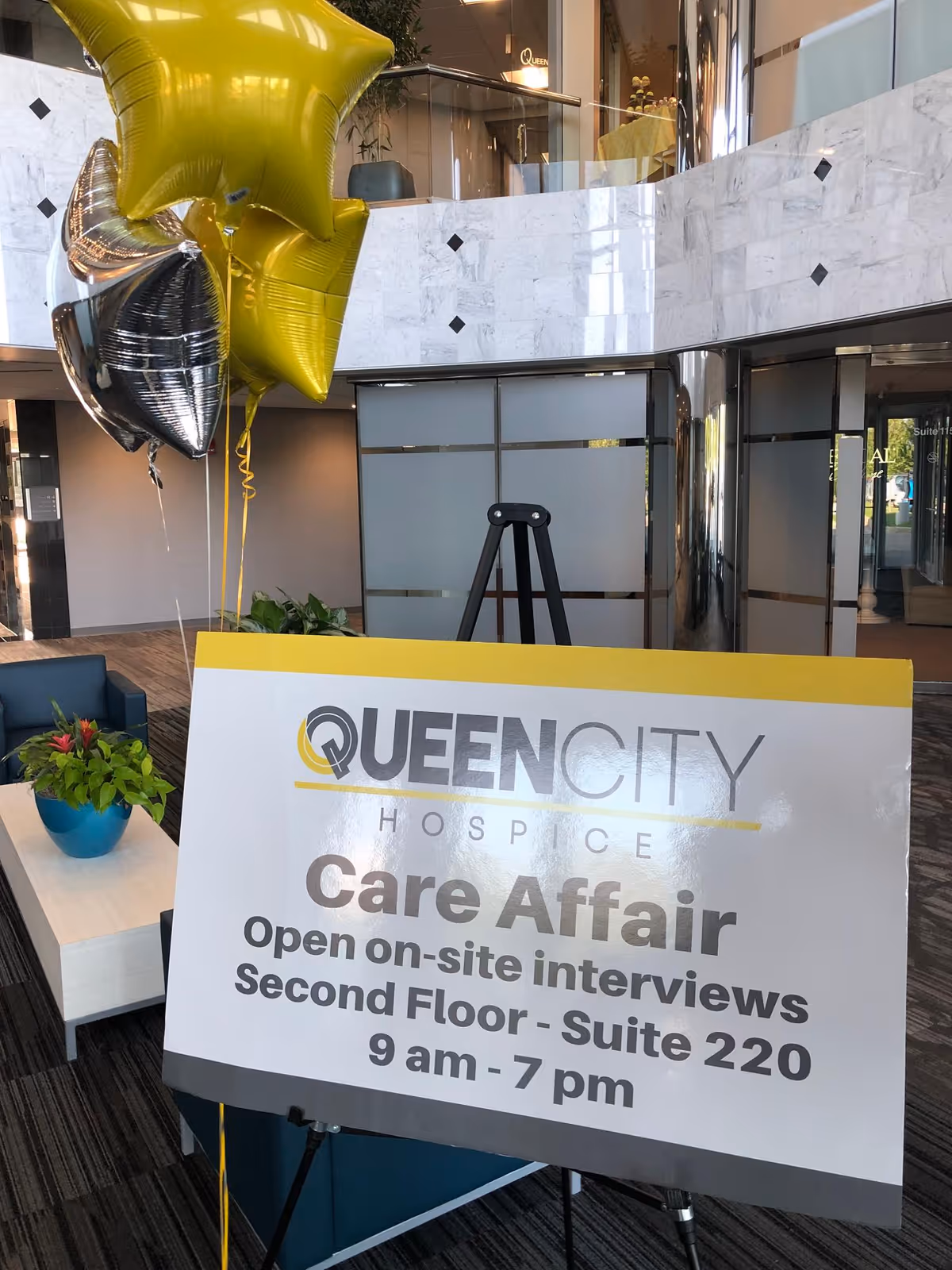 Lobby area with Queen City Hospice Care Affair sign and yellow balloons