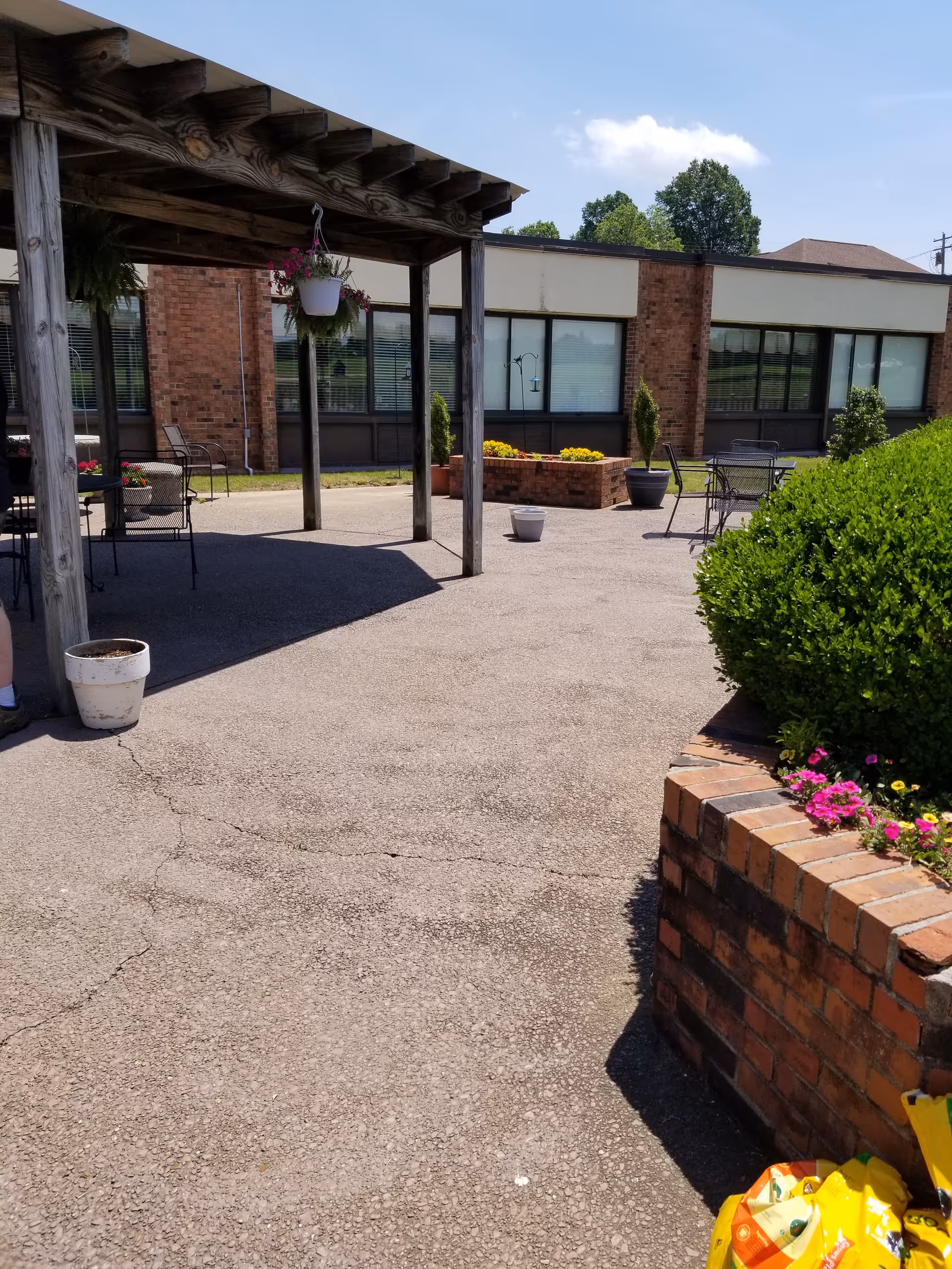 Outdoor courtyard at NHC Milan with a wooden pergola, seating, and brick planters.