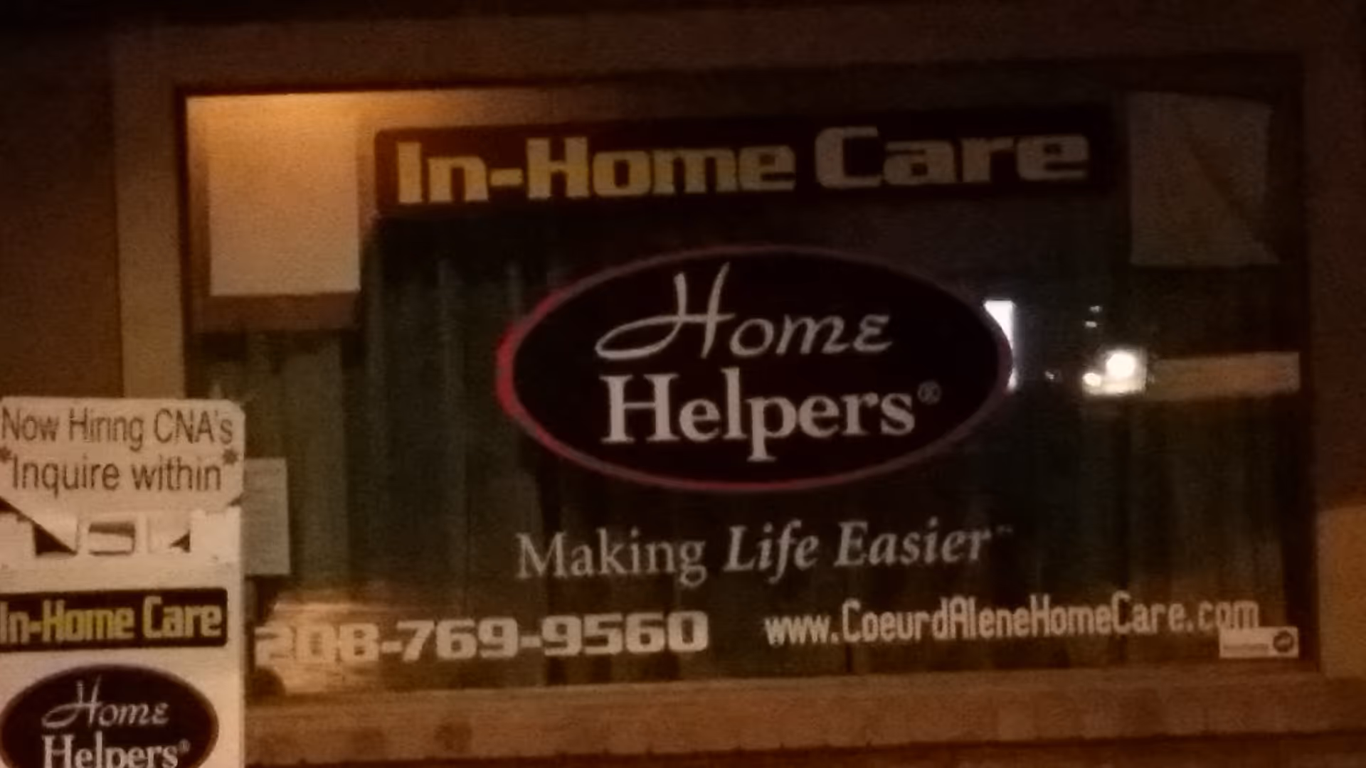Storefront window sign for Home Helpers In-Home Care with a hiring notice.