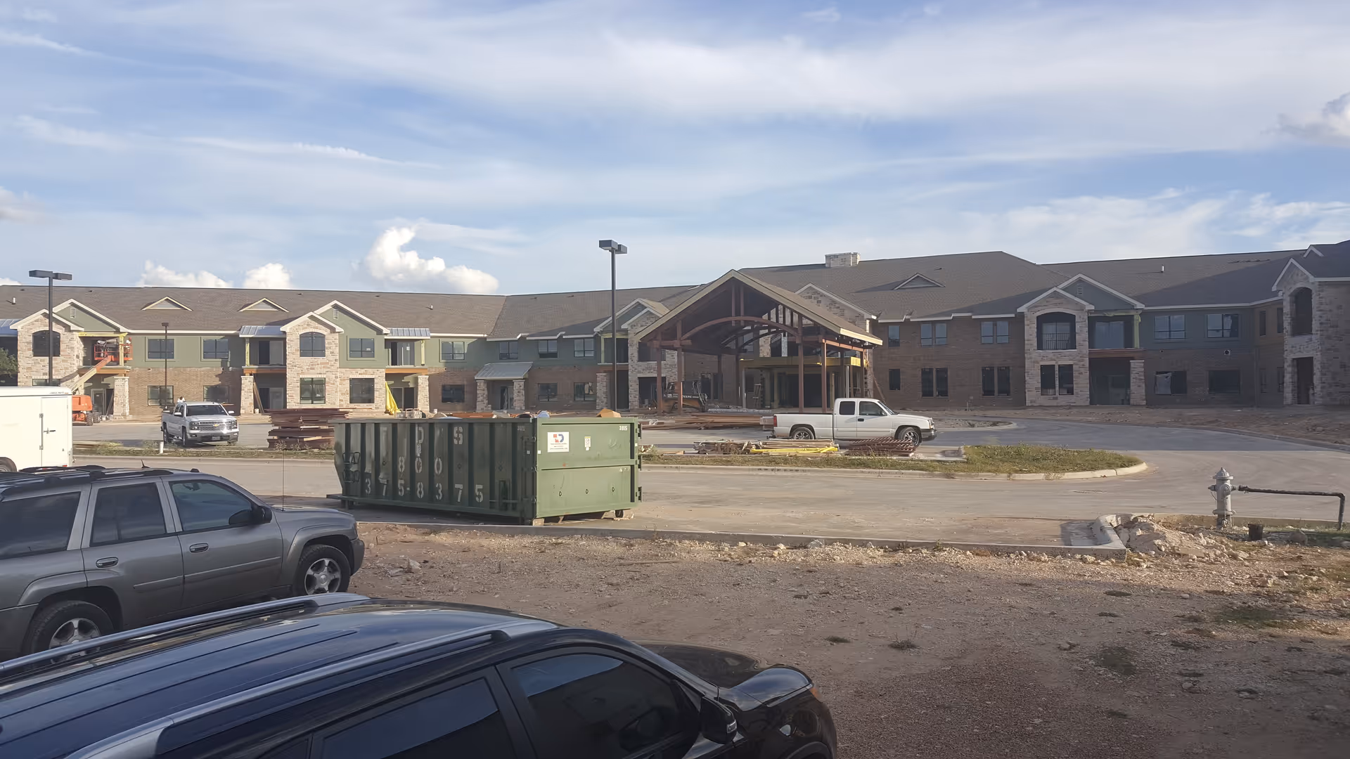 Exterior view of The Wesleyan Independent Living West under construction with parked vehicles.