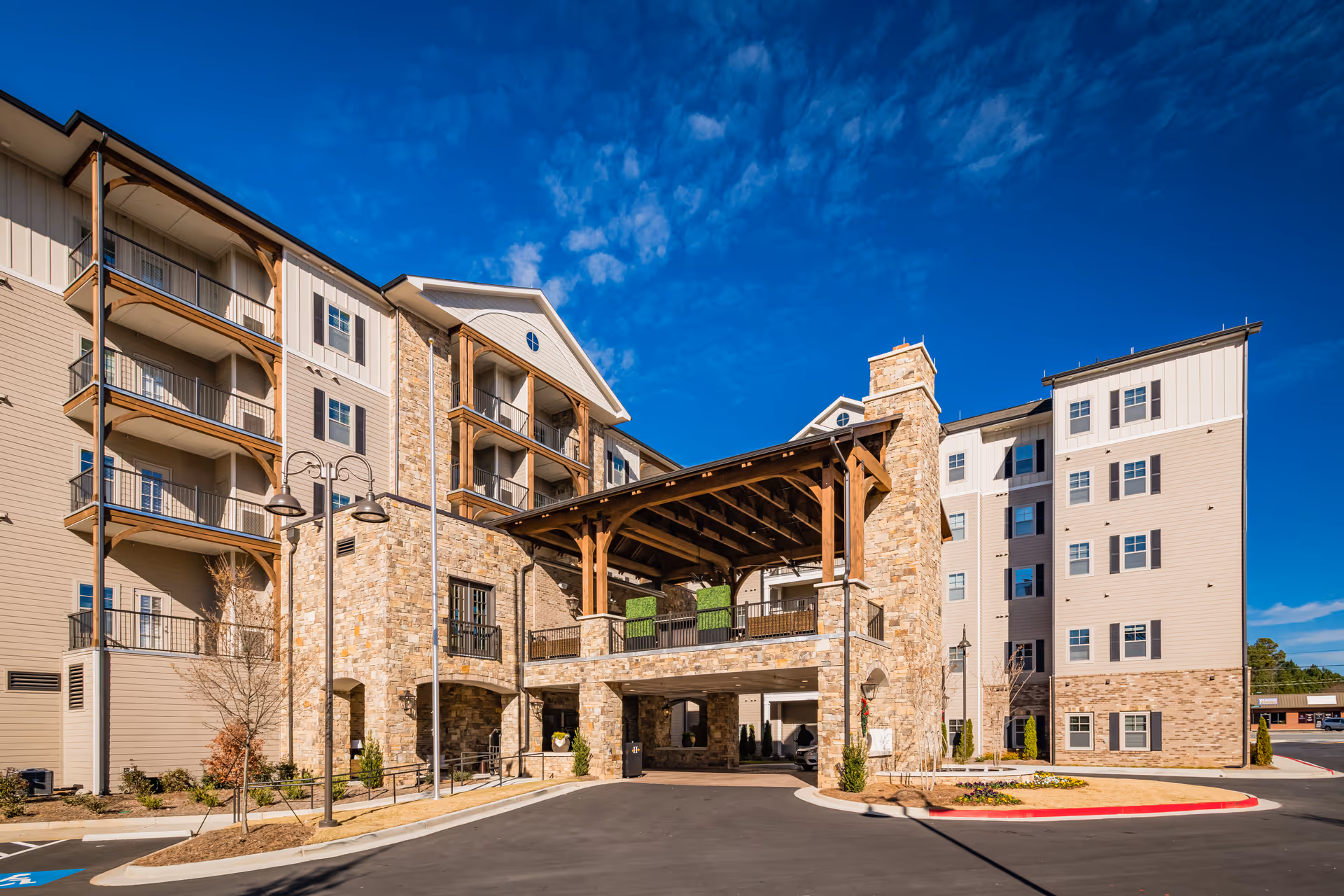 Exterior view of a multi-story assisted living building with a stone entrance and balconies.