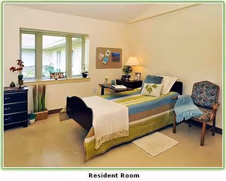Alden Estates resident room with bed, desk, chair, and window.