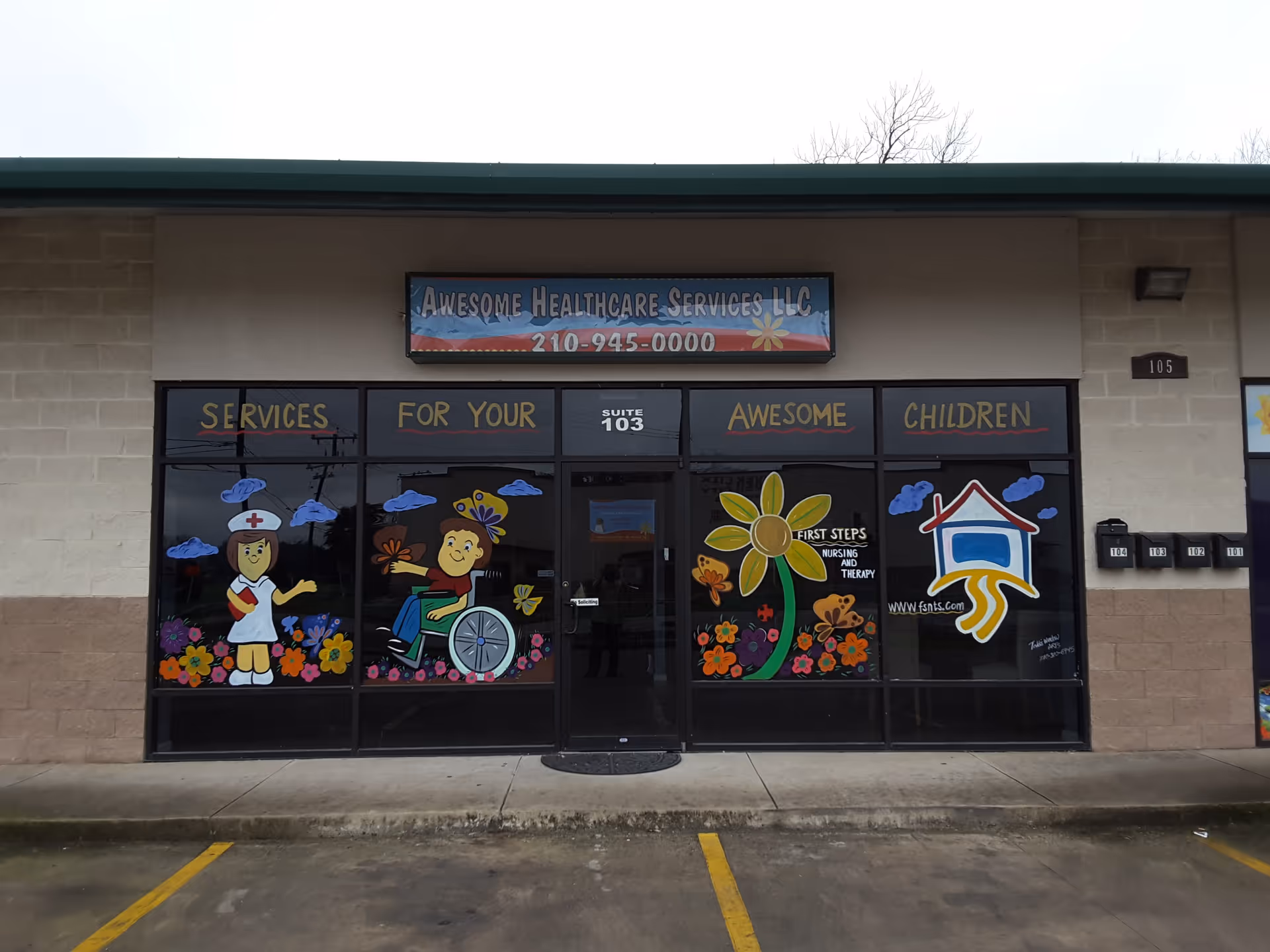 Front of a beige building with colorful window decals and signage advertising services.