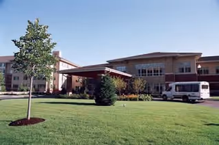 Exterior view of Linden Ponds with canopy entrance and parked bus.