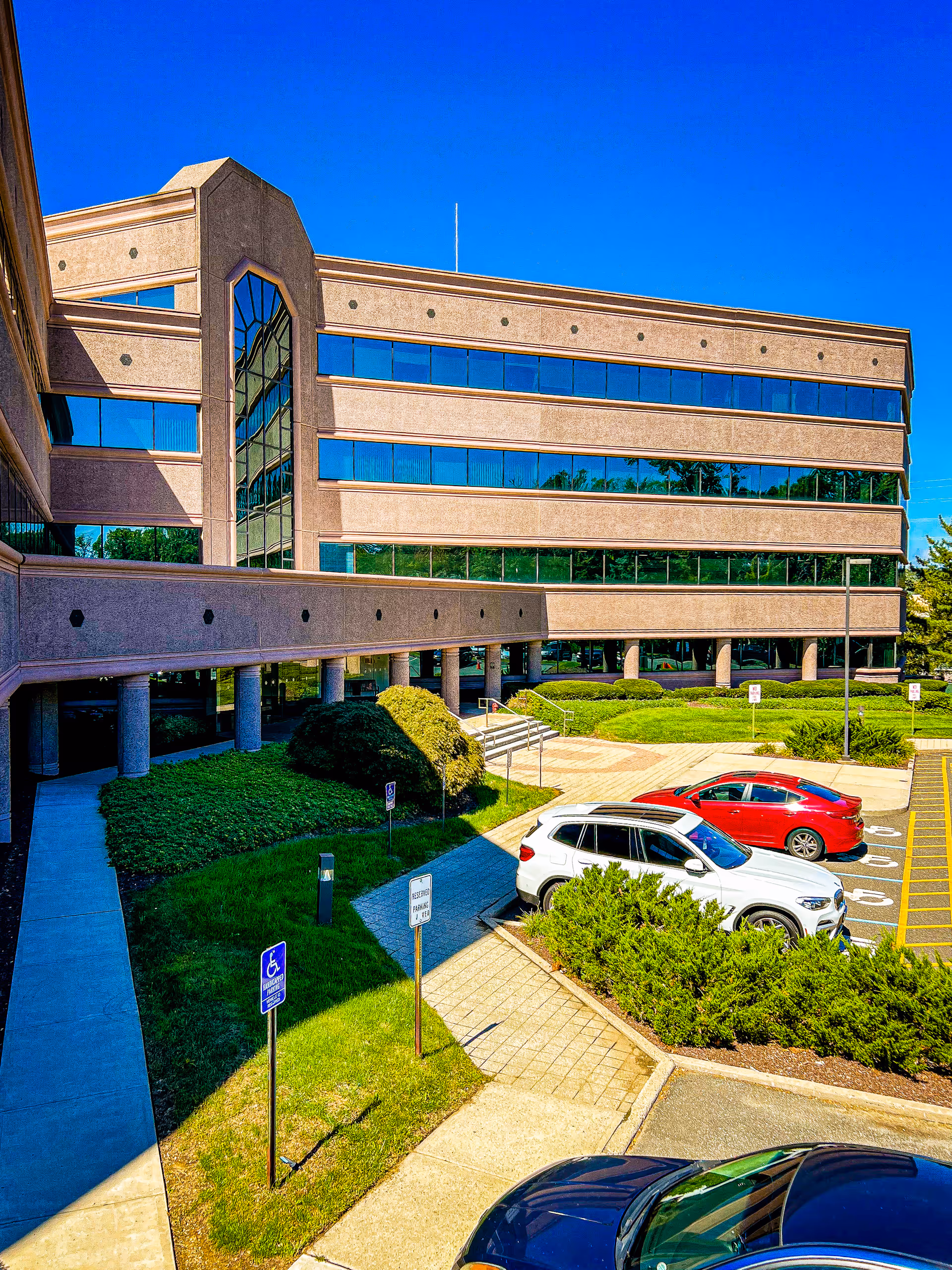 Exterior view of PathWell Home Health facility with glass windows, parking lot, and landscaped grounds.