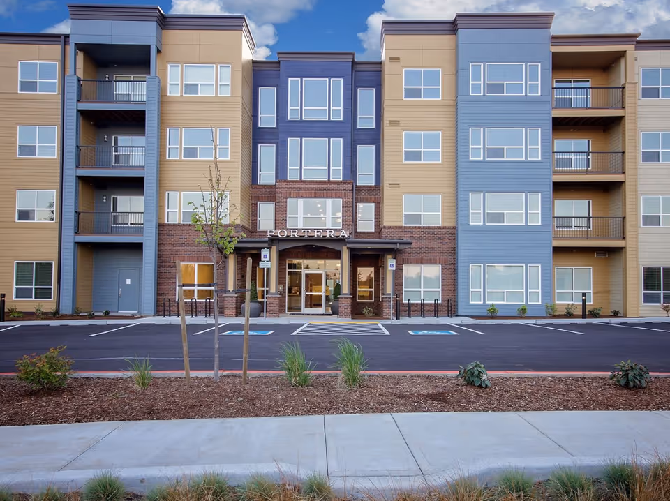 Exterior view of Portera at the Grove senior living building with balconies and a brick entrance.