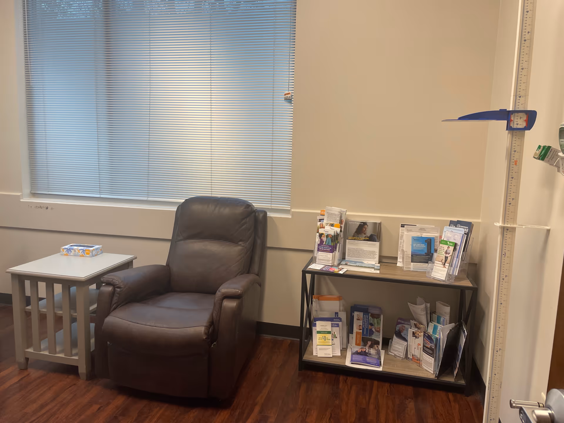 Brown leather armchair with a small side table and brochure rack in a quiet waiting area.