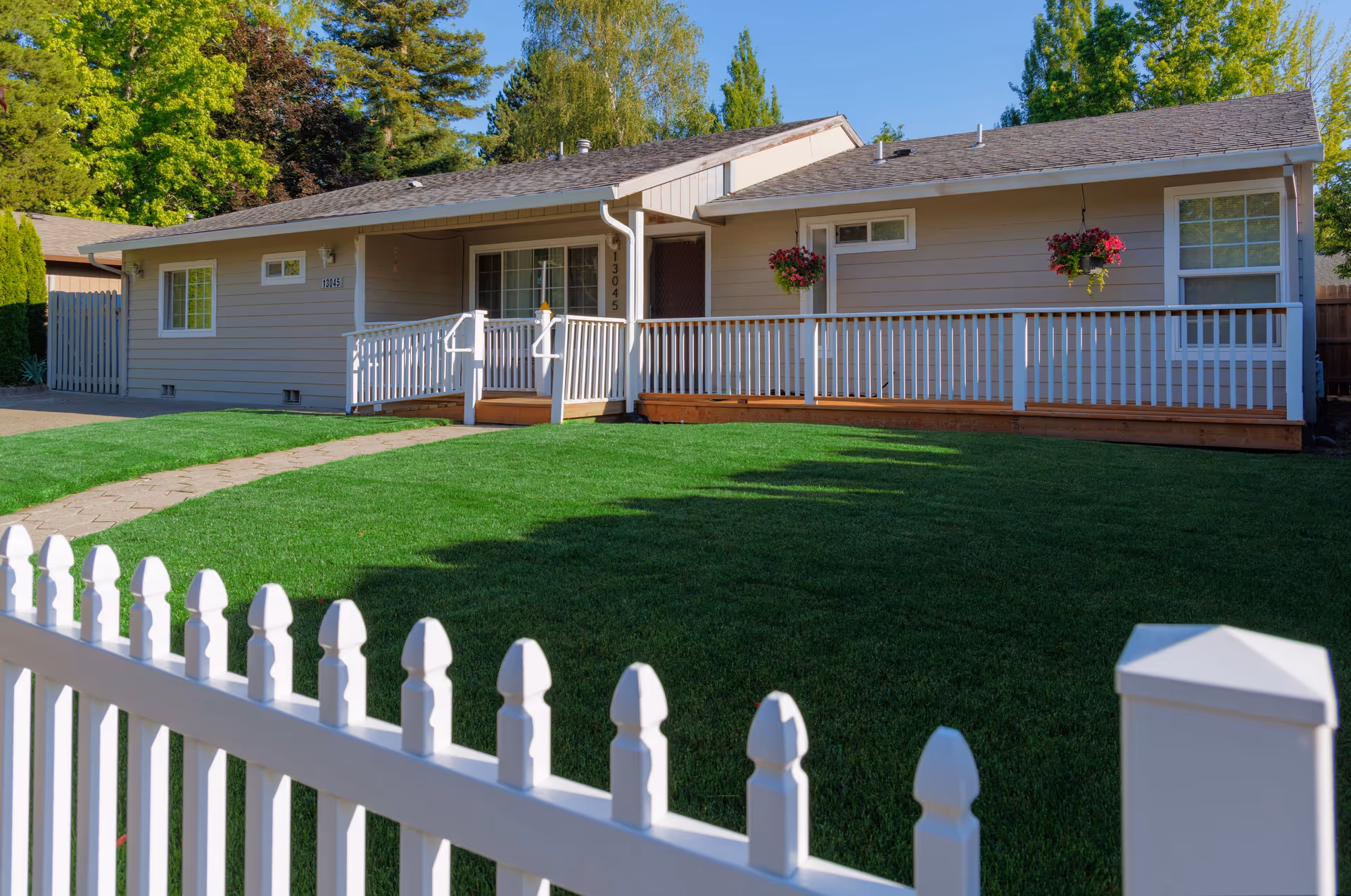 Single-story care home with a long front porch, white railings, and a manicured green lawn.