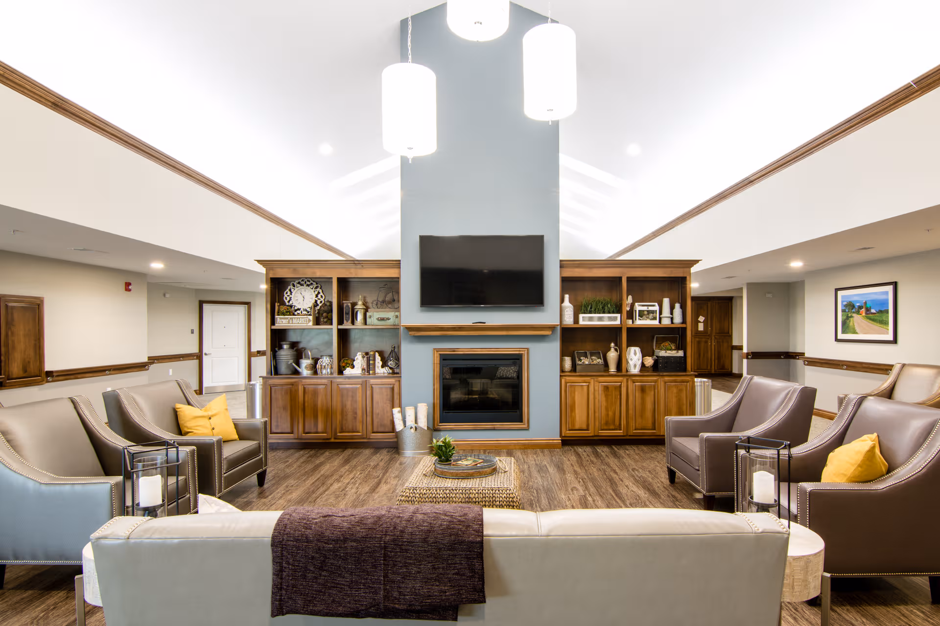 Bright lounge area with sofas, a fireplace, and built-in wooden shelves.