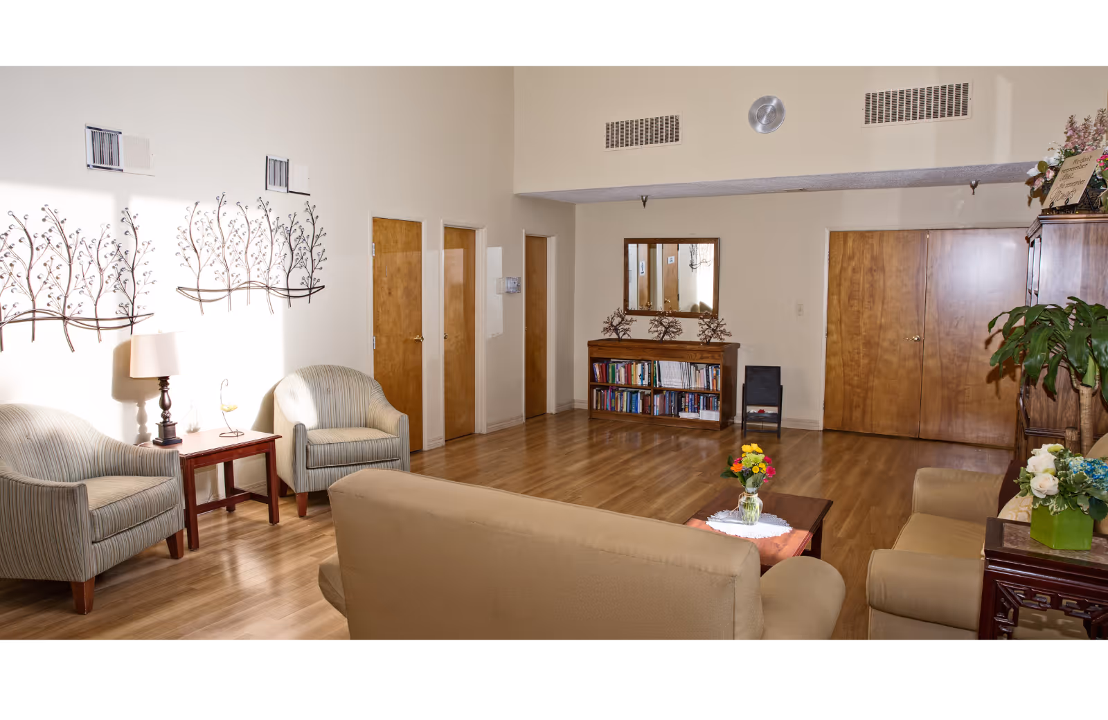 Sunny senior living lounge with seating, a coffee table, and a bookshelf.