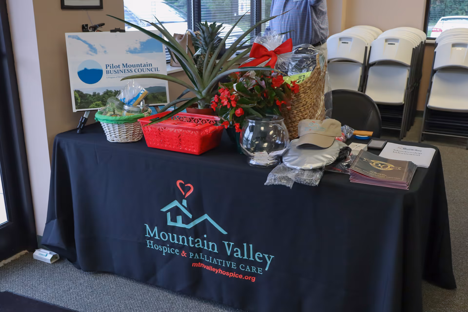 Table draped with Mountain Valley Hospice banner, with plants, baskets, and brochures.