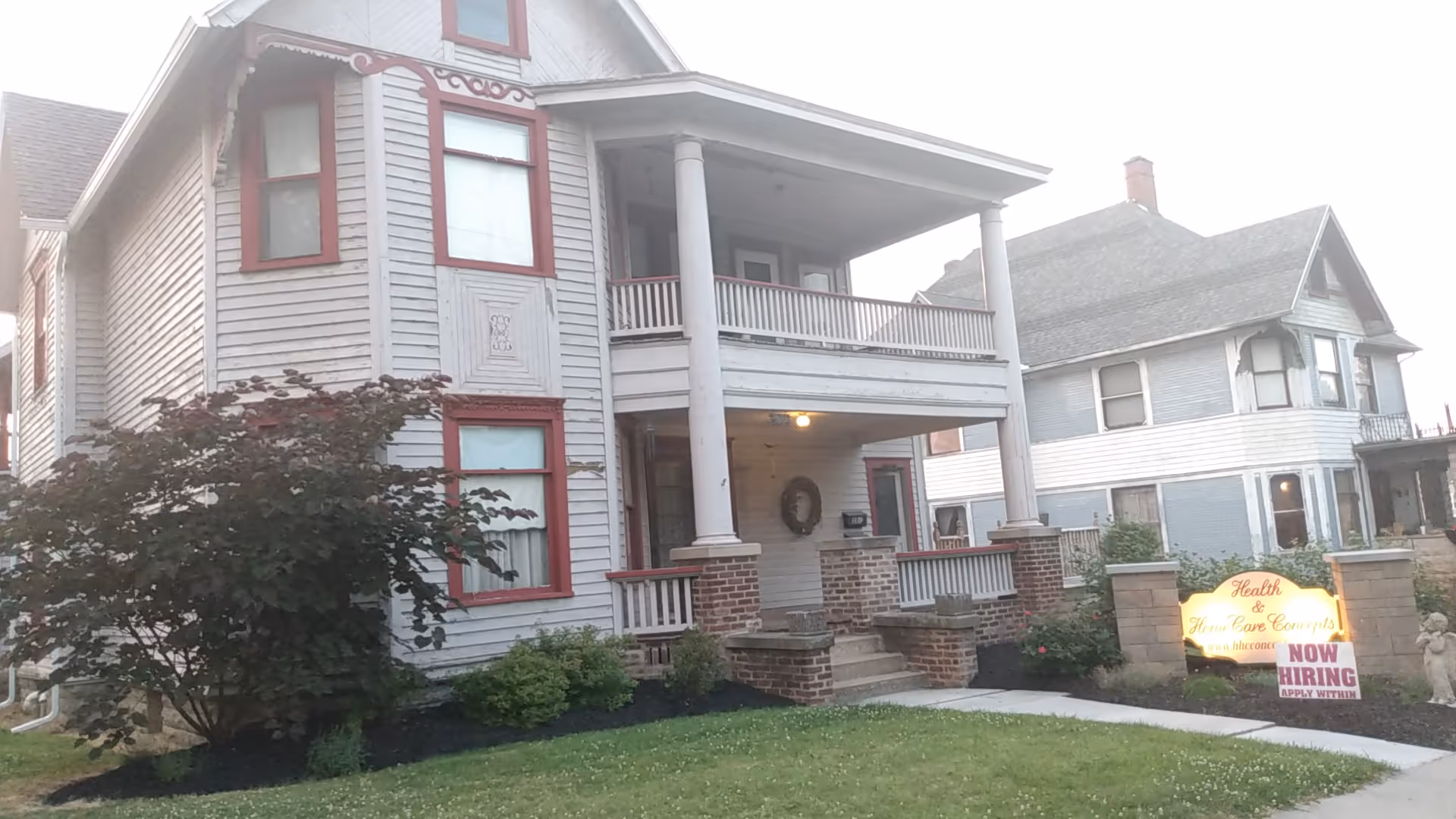 Two-story light-gray house with front porch and Health & HomeCare Concepts sign.
