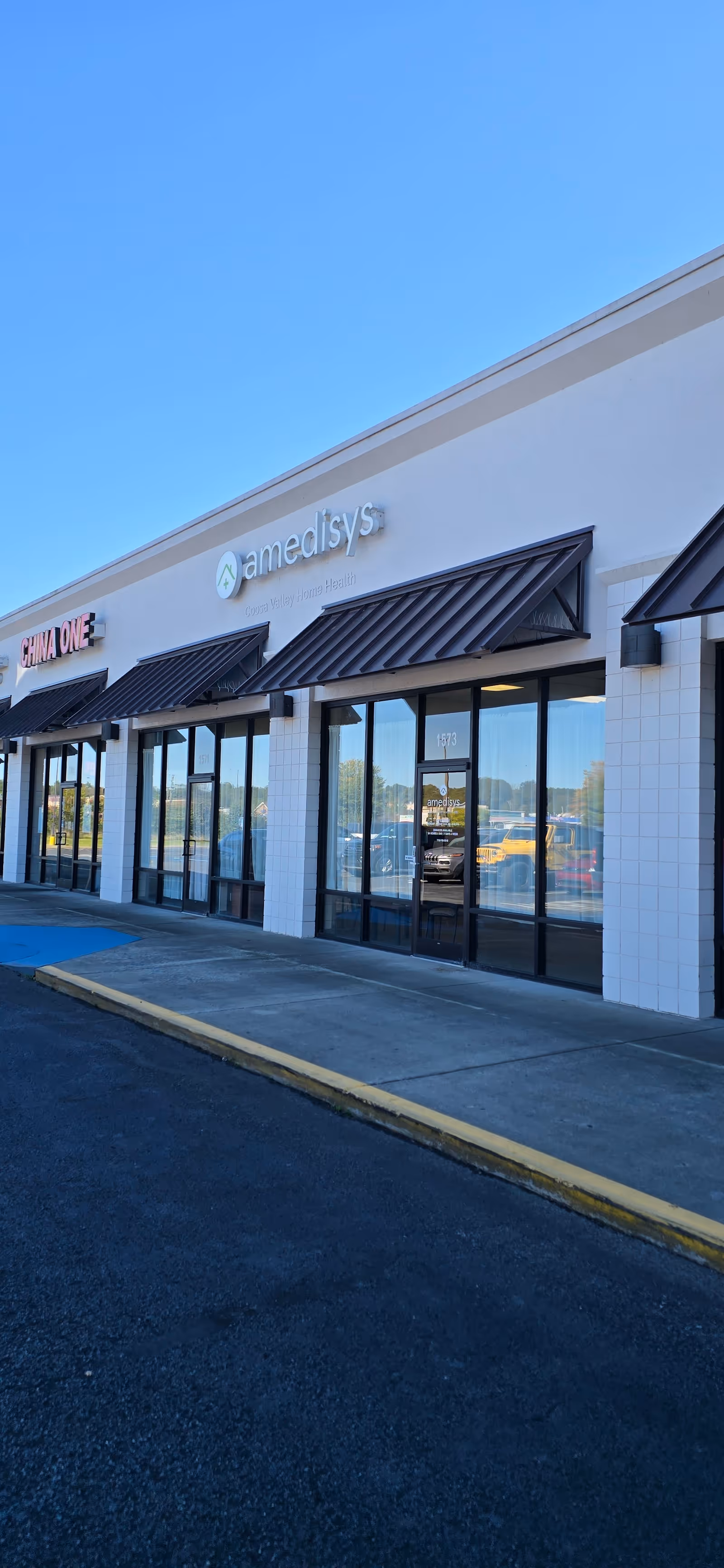 Exterior view of a building with Amedisys sign and storefront windows.