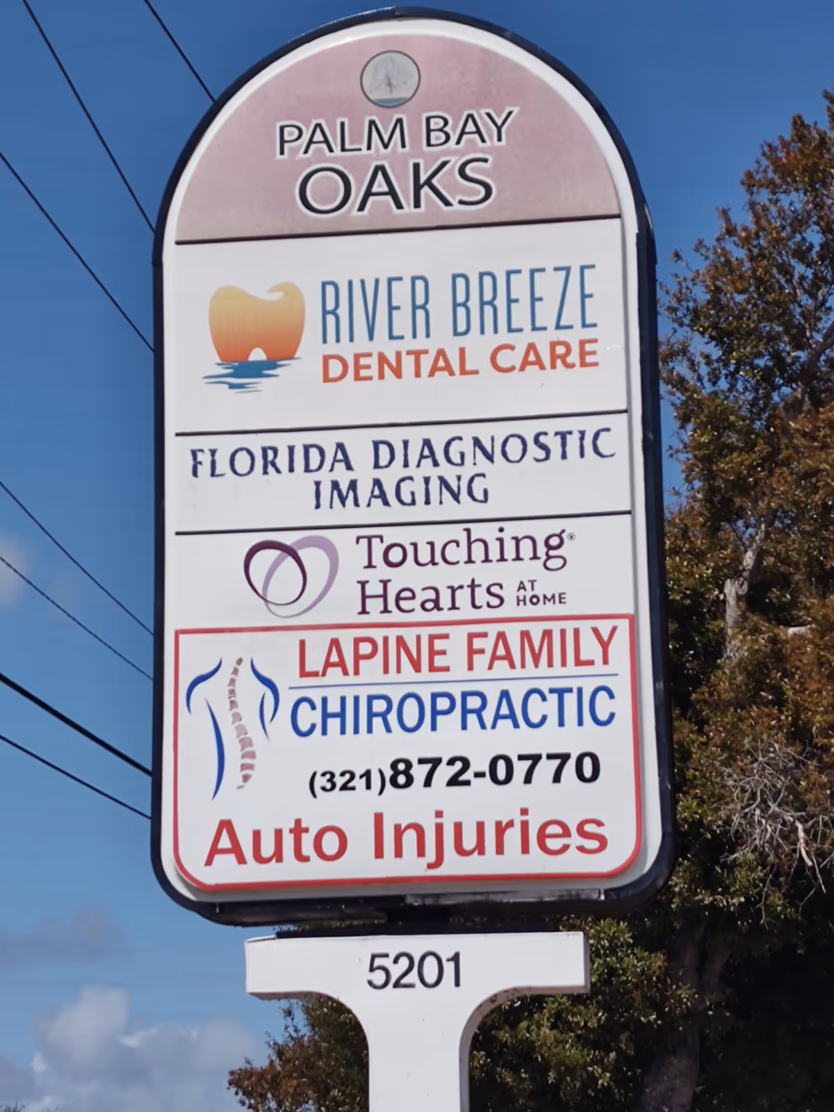 Tall outdoor signboard listing multiple businesses including Touching Hearts at Home