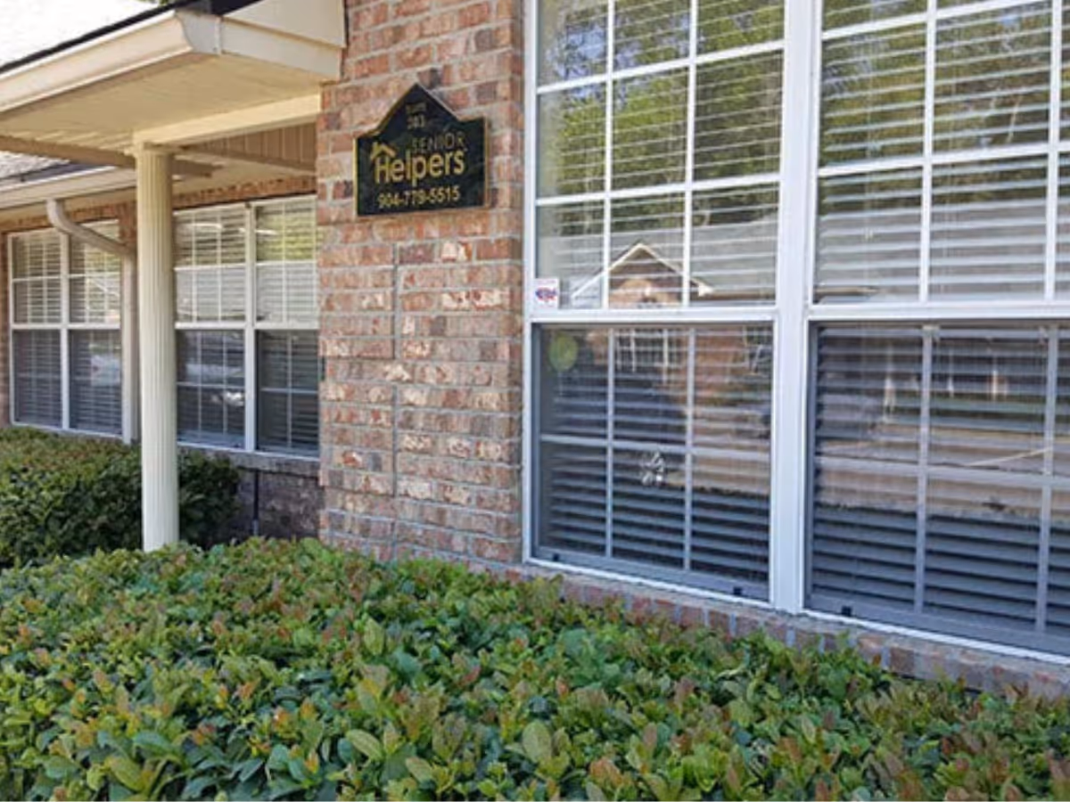 Exterior view of a brick senior facility with a Senior Helpers West Jacksonville sign and windows.