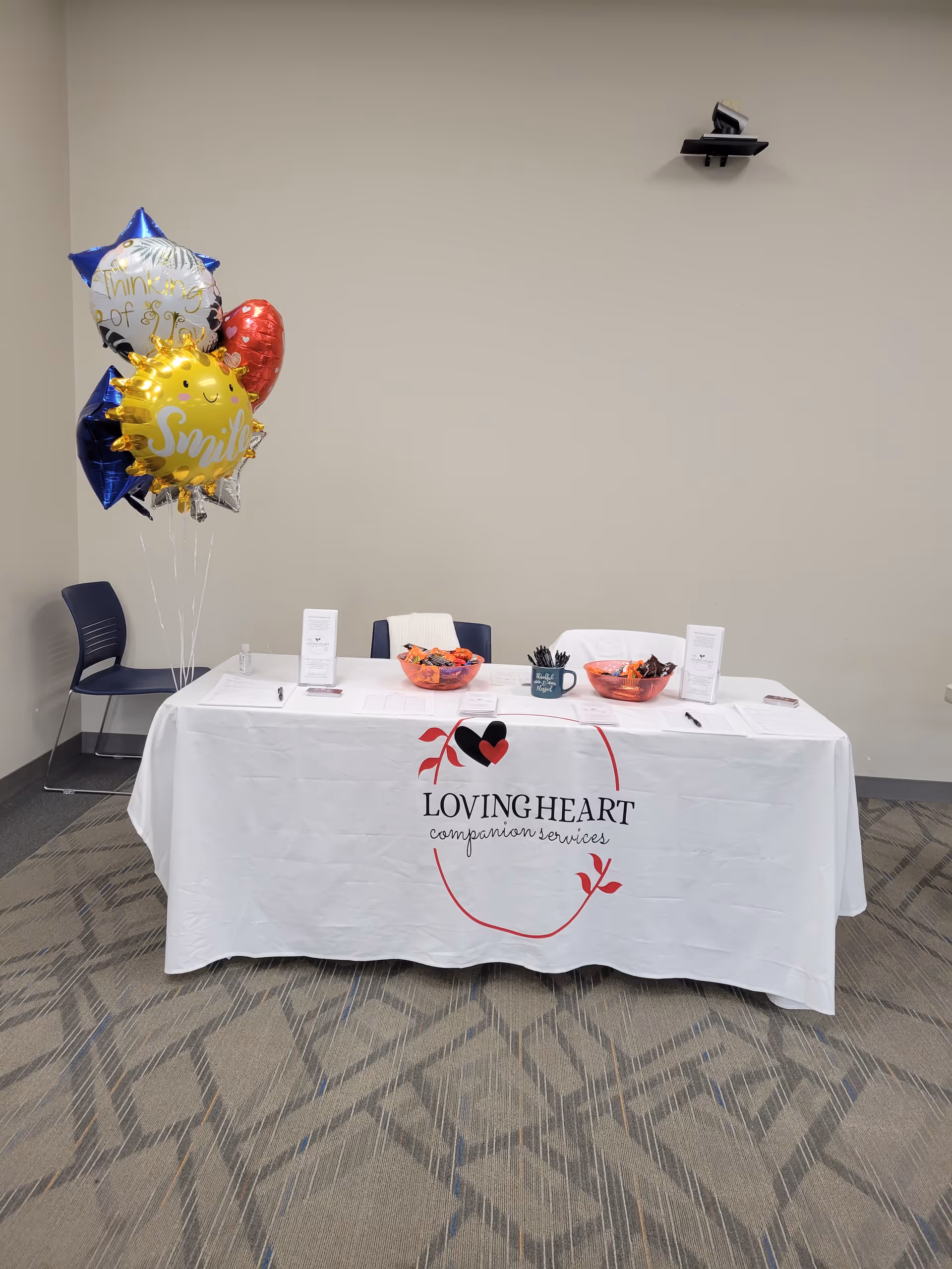 Indoor table with Loving Heart banner, balloons, and bowls of treats.