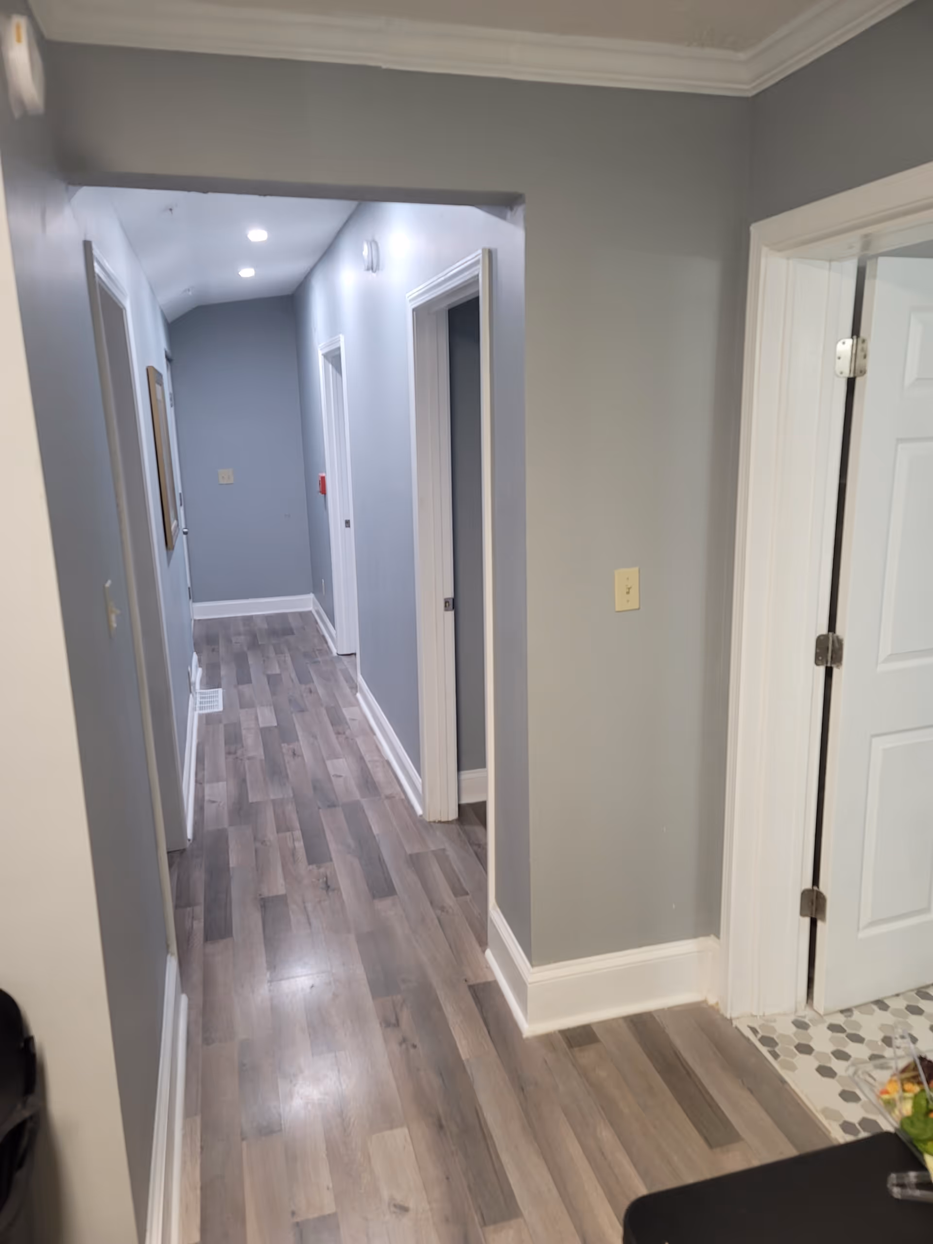 Interior corridor in a senior living facility with doors and gray walls.