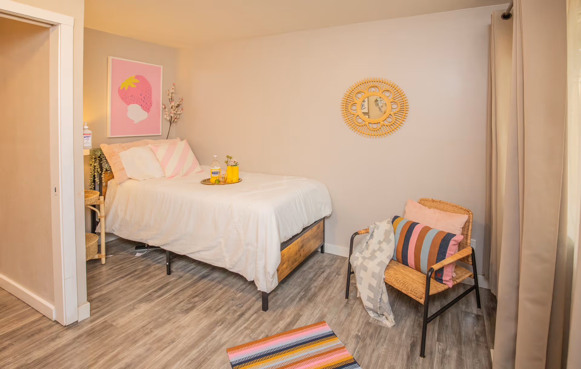 Bright senior living bedroom featuring a bed, cozy chair, wall art, and soft curtains.