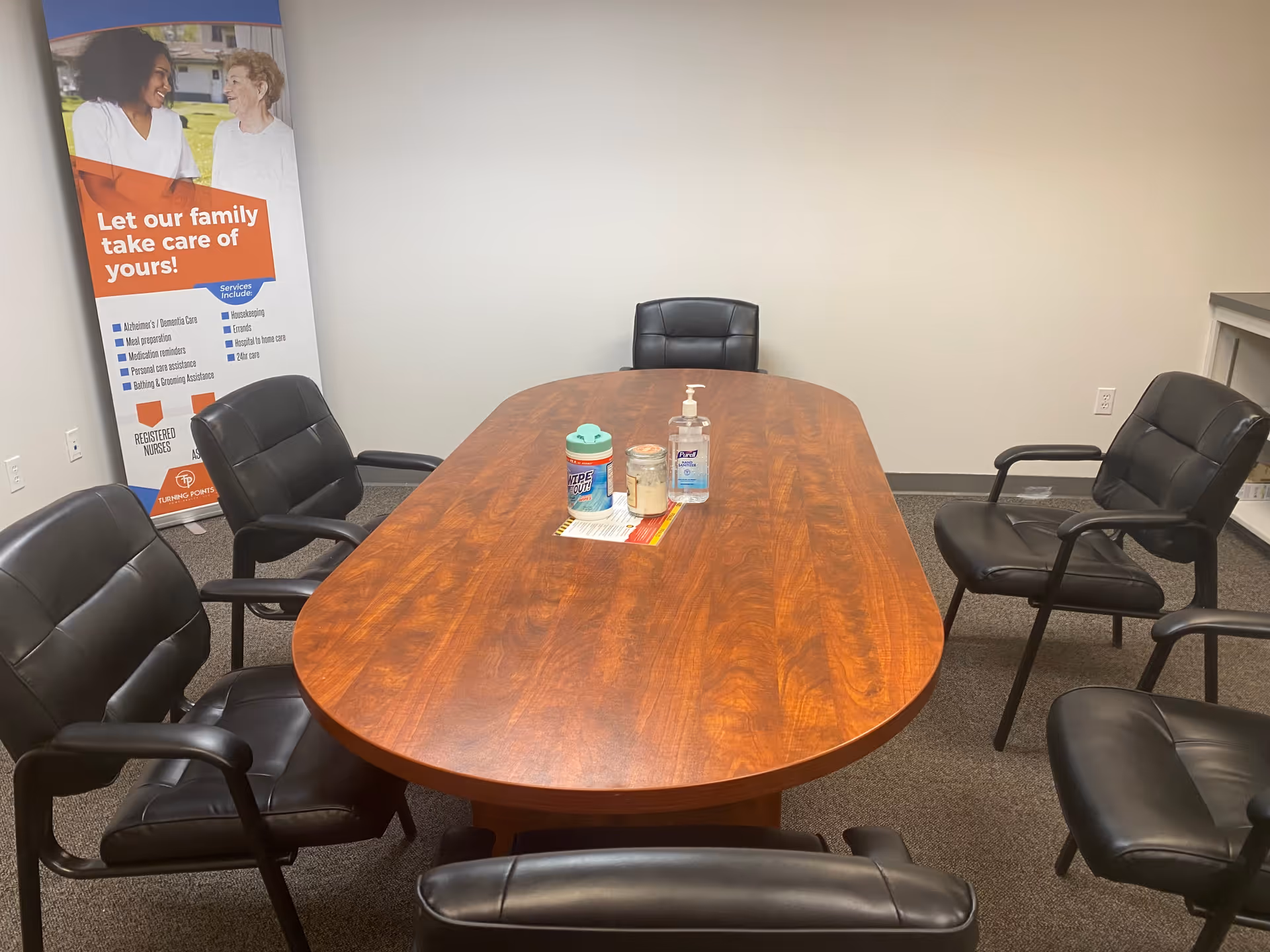 A conference room in a senior living facility with an oval wooden table and leather chairs.