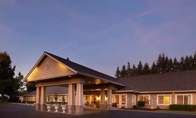 Exterior view of Martin House senior living facility entrance with covered drop-off at dusk.