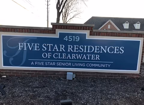 A large blue entrance sign reading "Five Star Residences of Clearwater" with the address 4519 mounted on a brick wall in front of landscaping.
