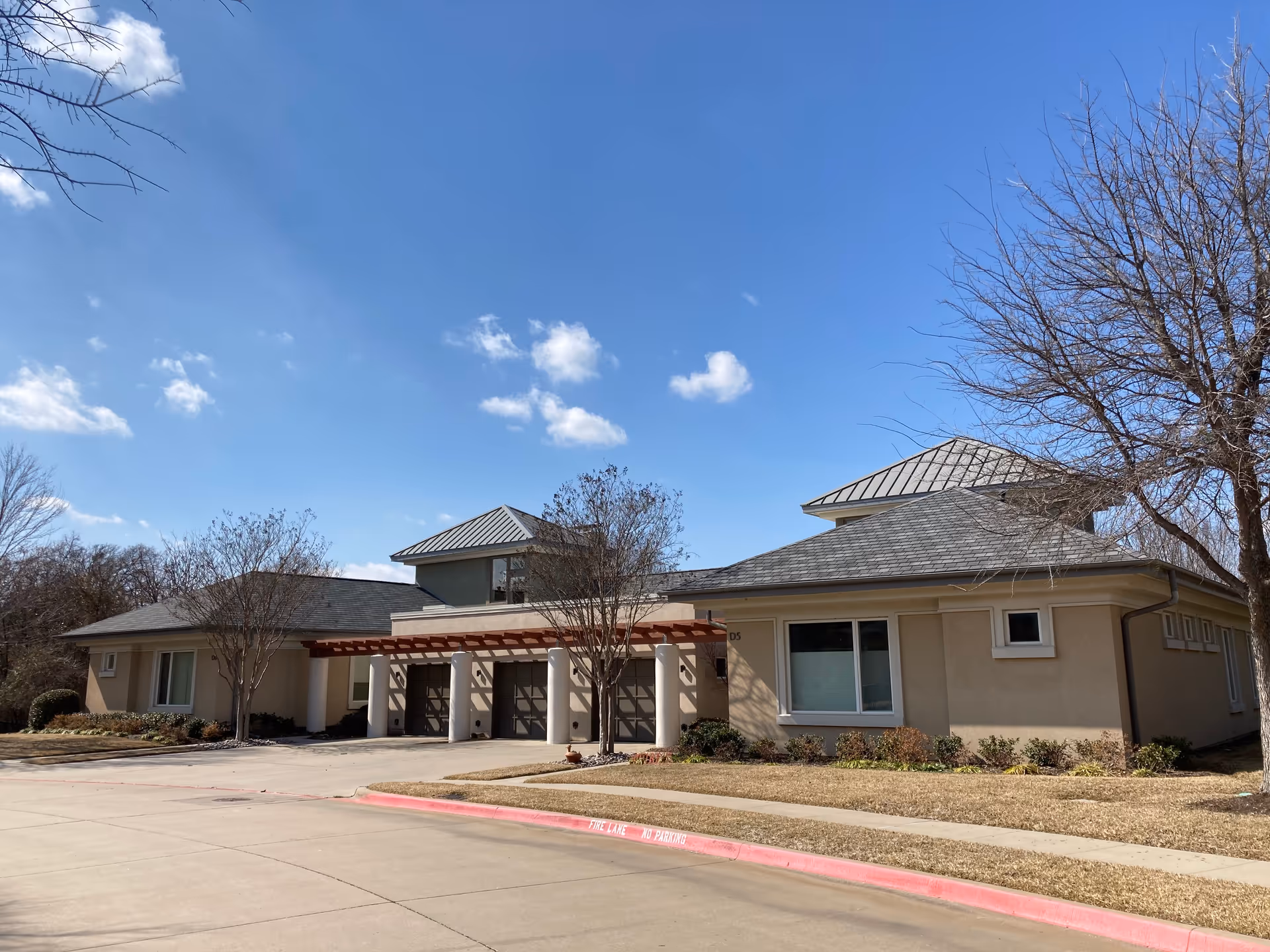 Exterior view of The Legacy Willow Bend facility with a covered entrance and surrounding landscaping.