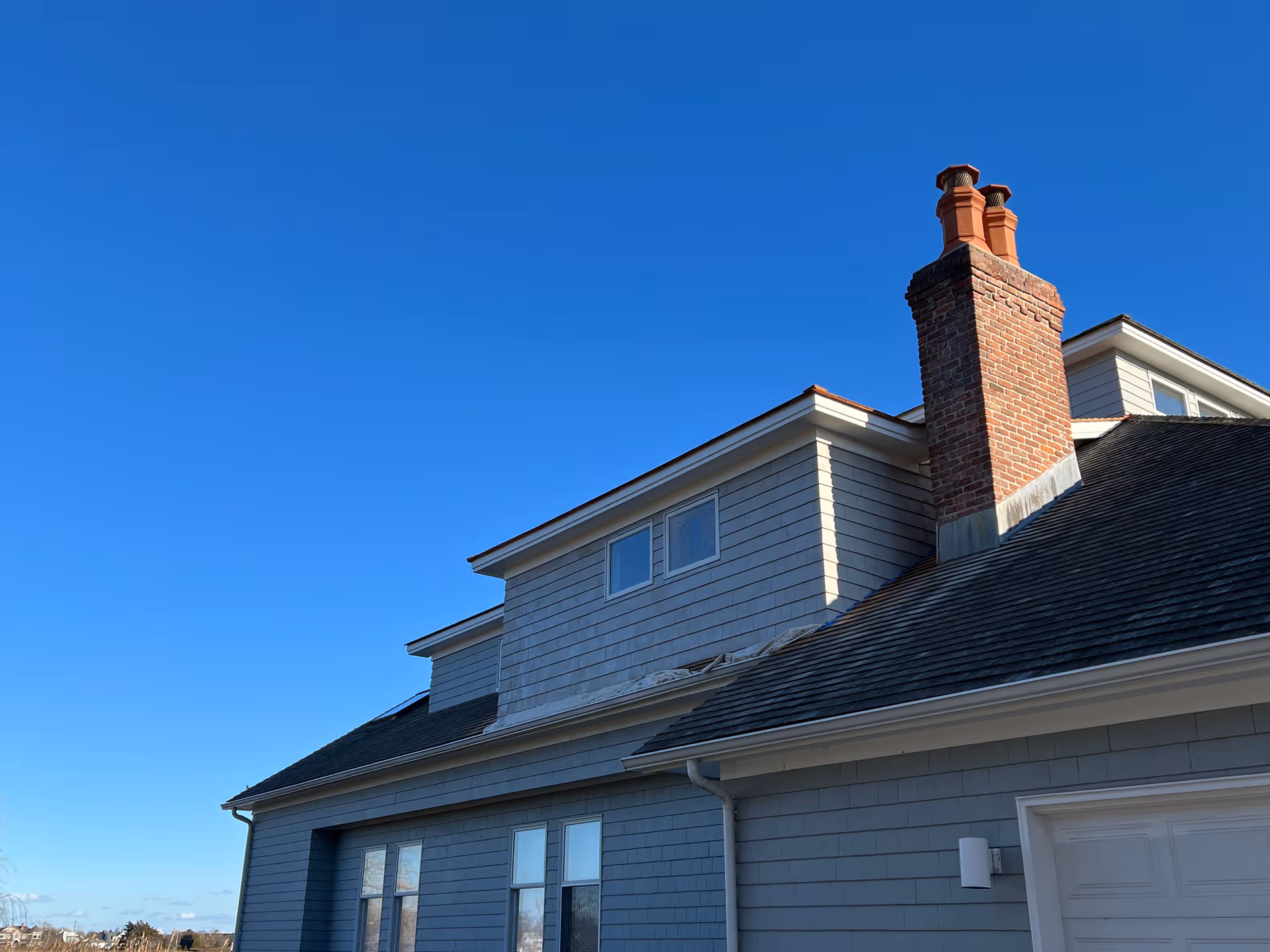 Blue gray senior living facility exterior with a brick chimney under a clear blue sky.